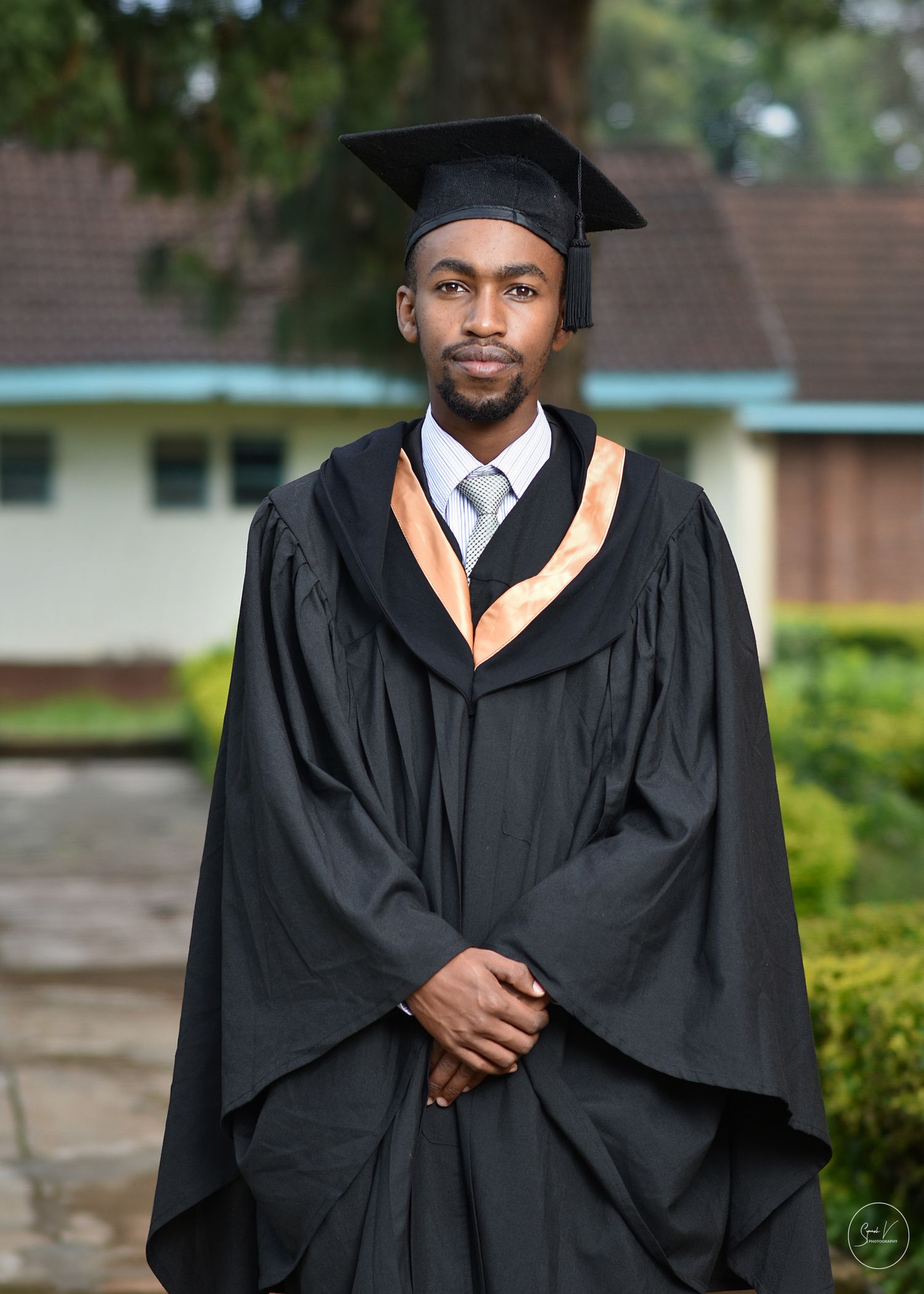 Strathmore University graduation photography - graduate in black gown posing triumphantly at the campus
