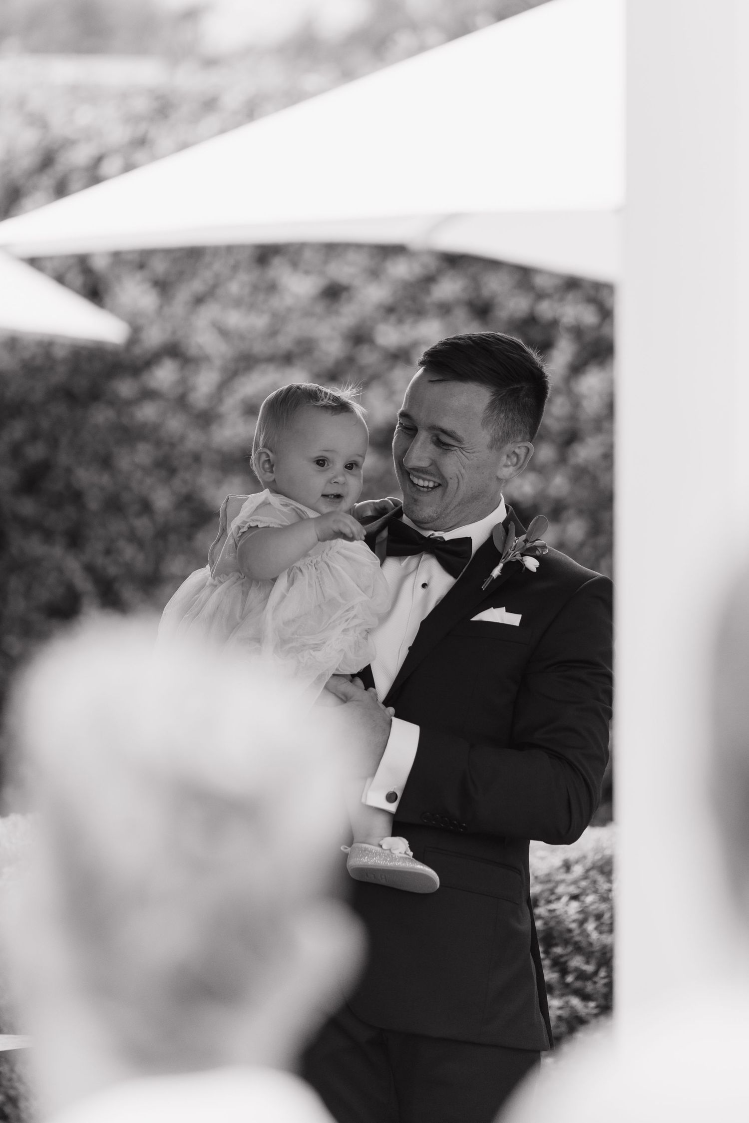 An intimate black and white portrait captured during a wedding celebration outdoors.