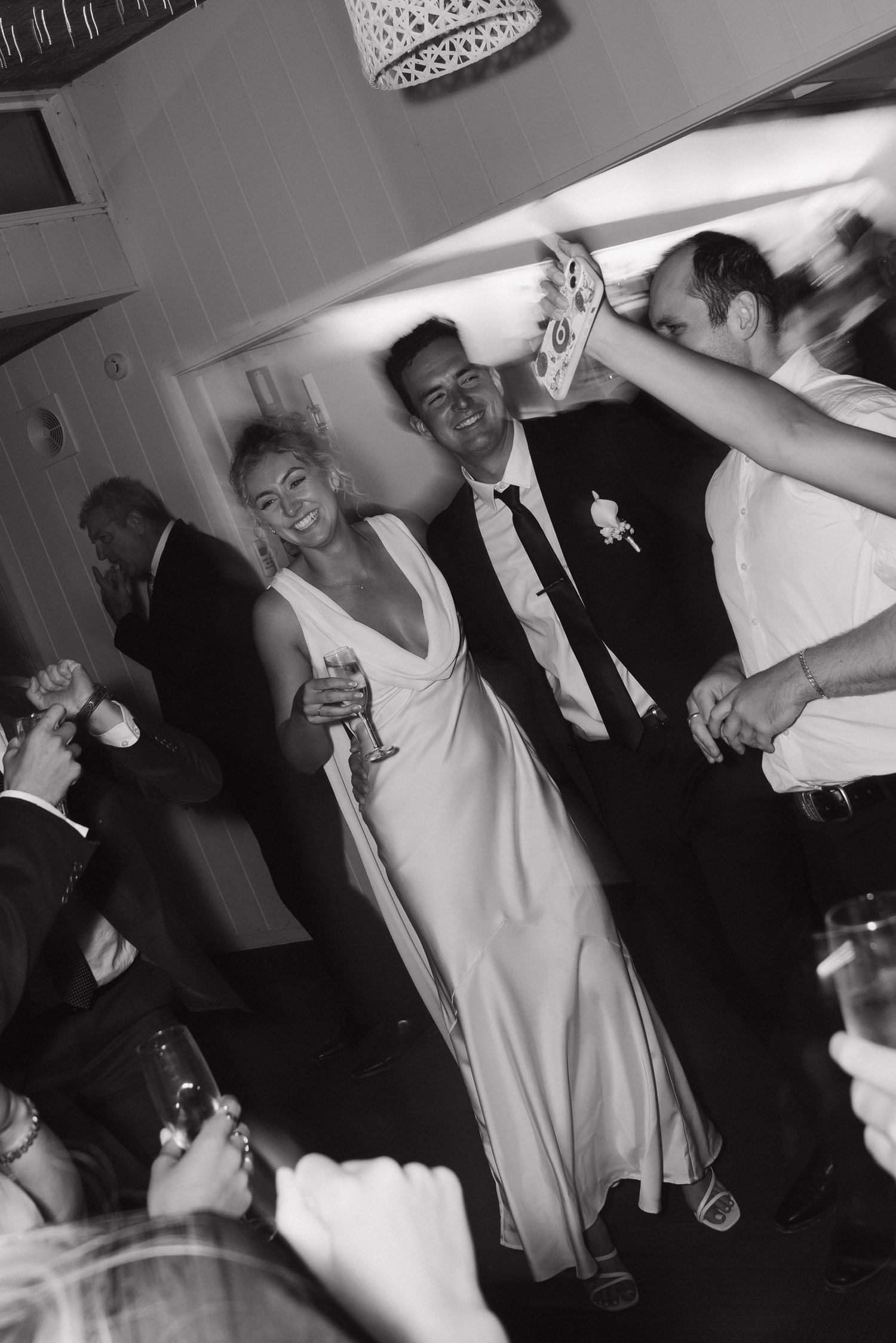 Wedding reception party guests dancing energetically in black and white photography.