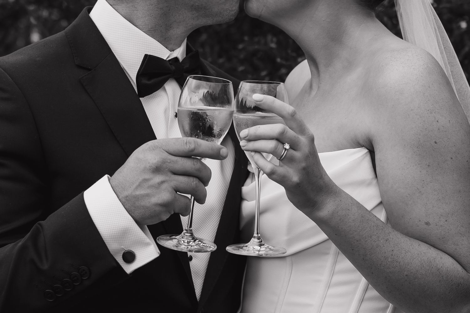 Elegant wedding toast between formally dressed couple holding champagne glasses.