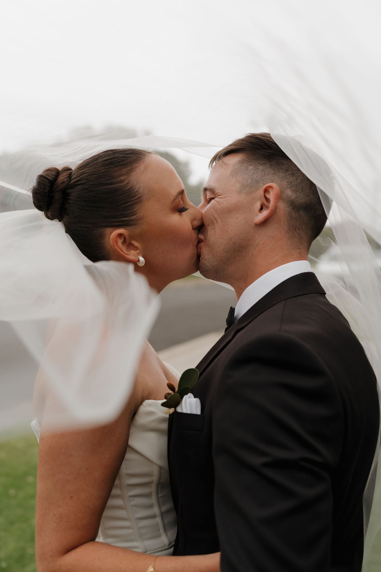 A romantic wedding kiss captured under a flowing white veil.