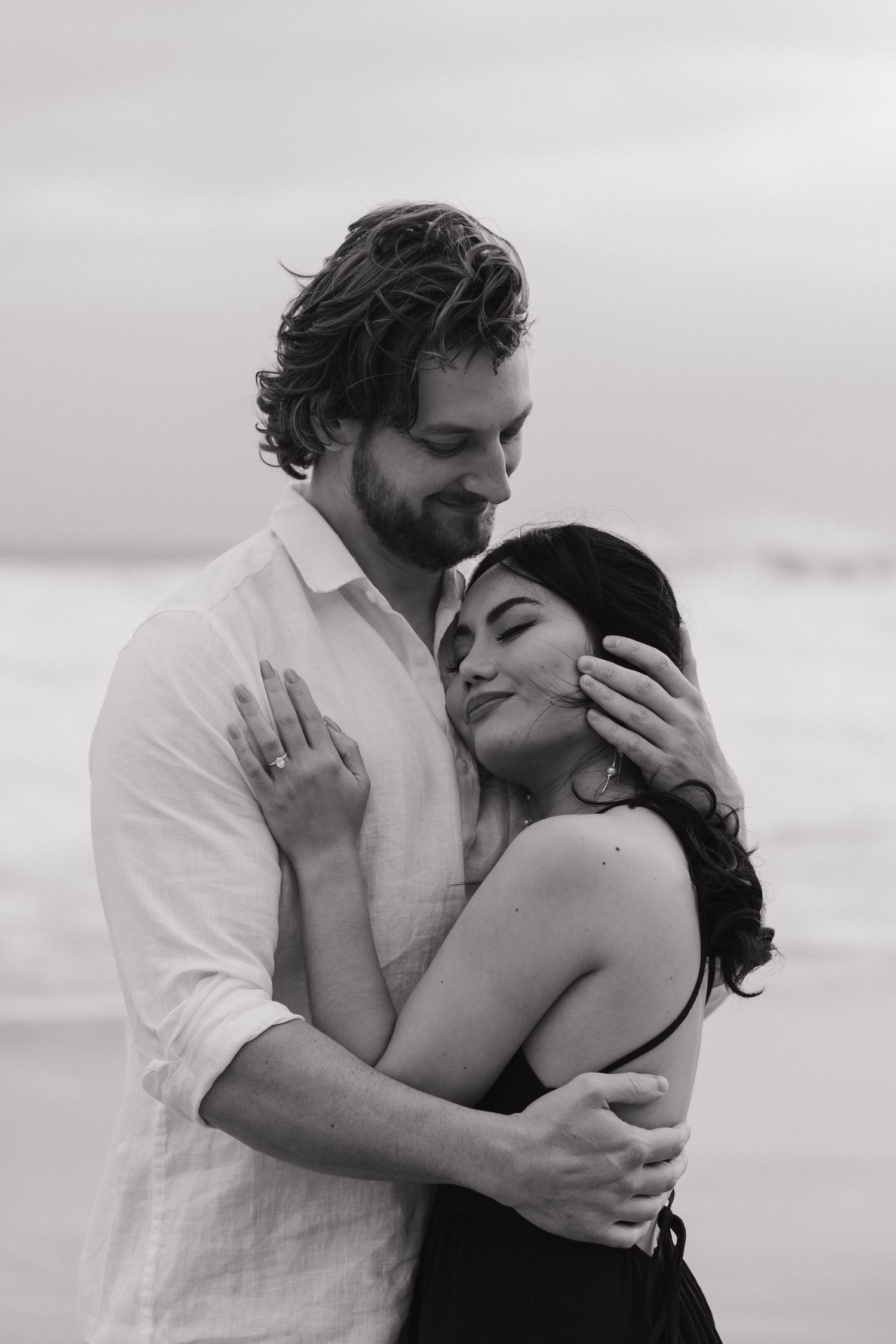Black and white beach portrait of couple sharing tender moment.