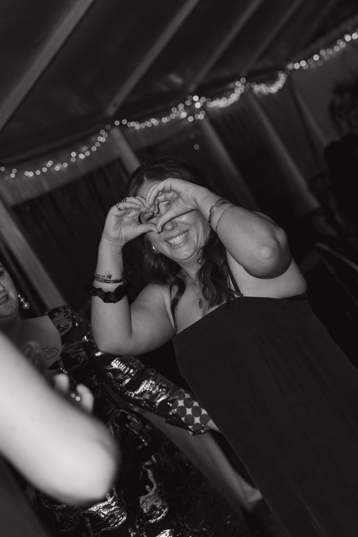 Wedding reception dance party with guests celebrating in black attire under dim lighting.
