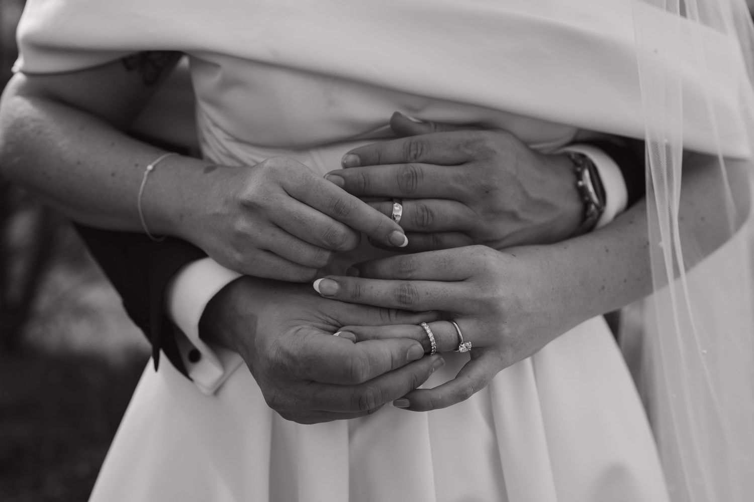 Close-up black and white photo of hands with wedding rings.