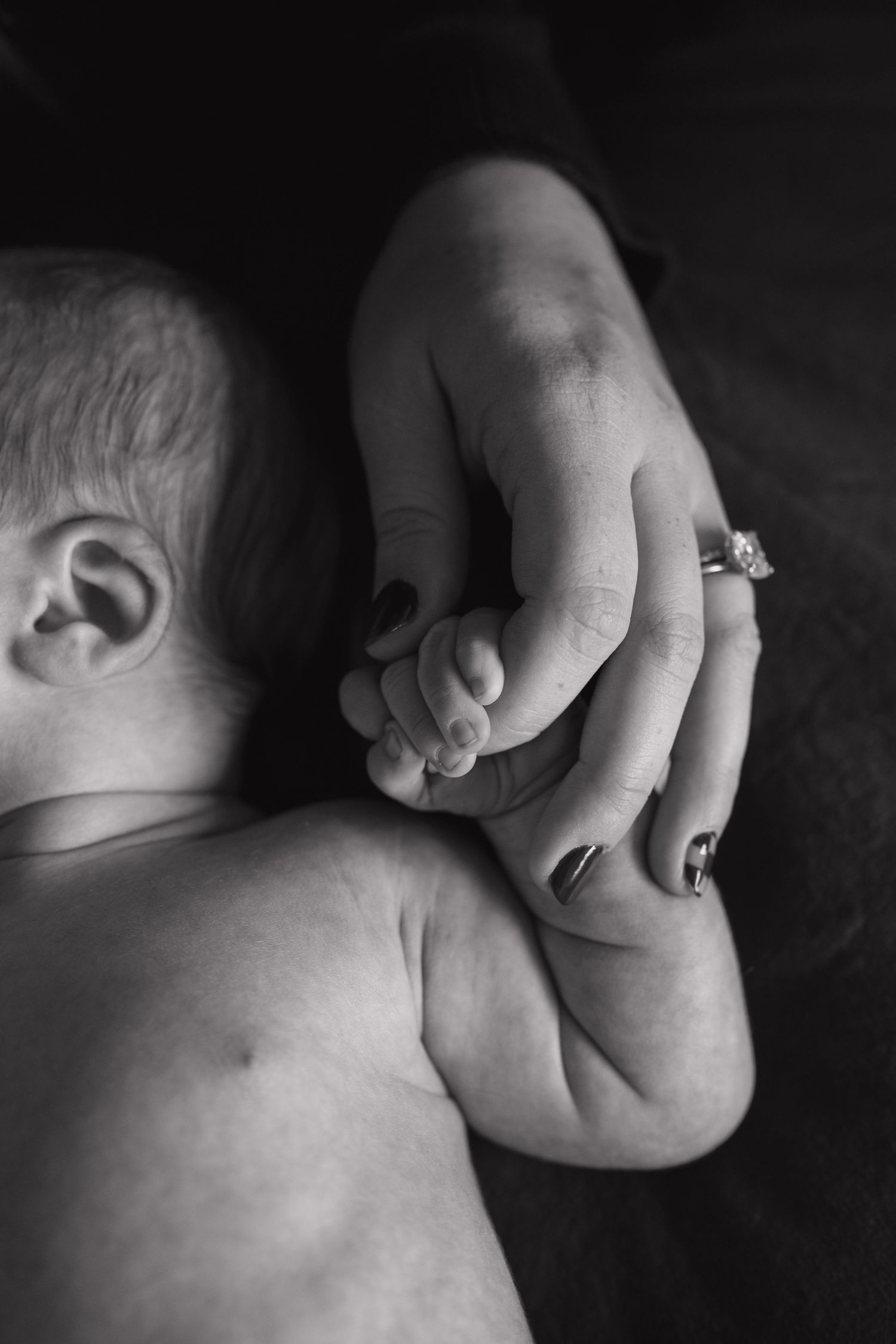 Black and white close-up of infant's delicate hand and body details.