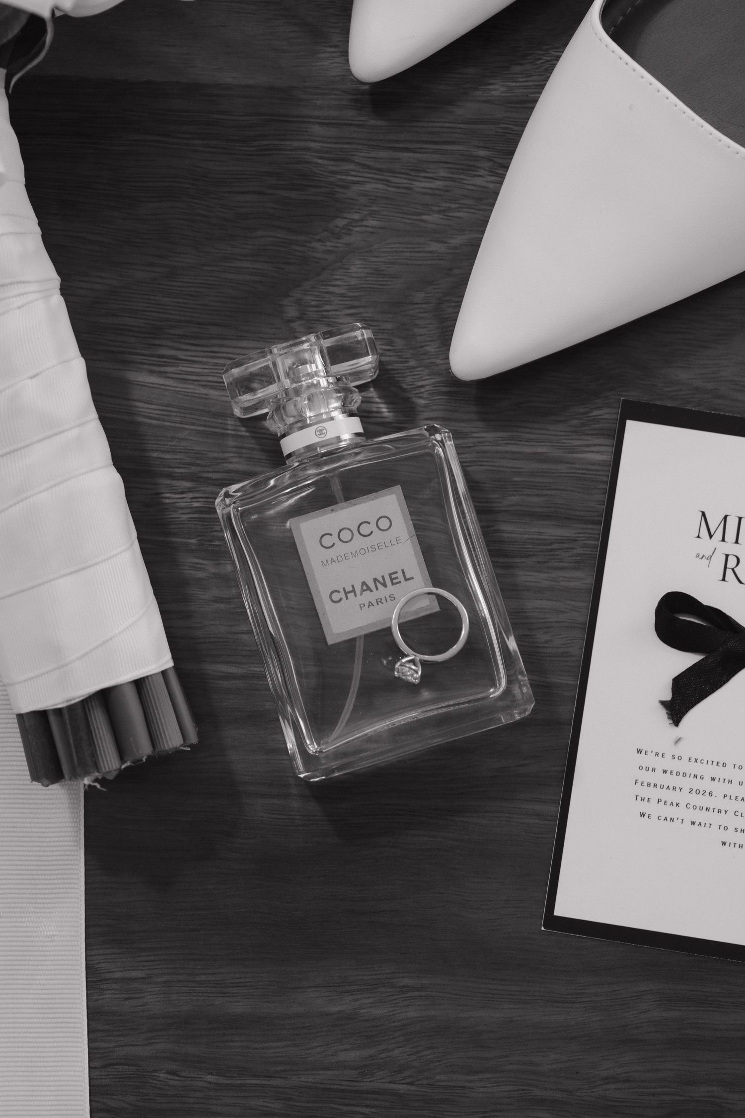 Luxury perfume bottles and wedding accessories arranged on dark wooden surface.