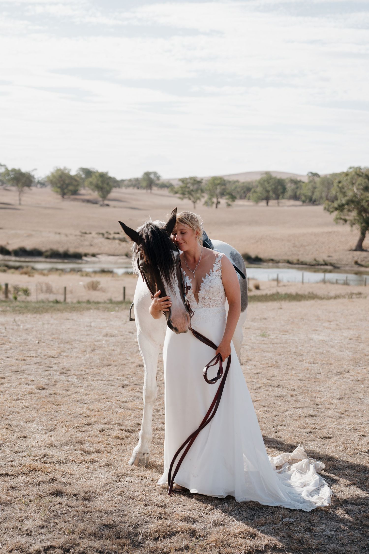 Couple shares intimate moment with horses in a rustic outdoor setting.