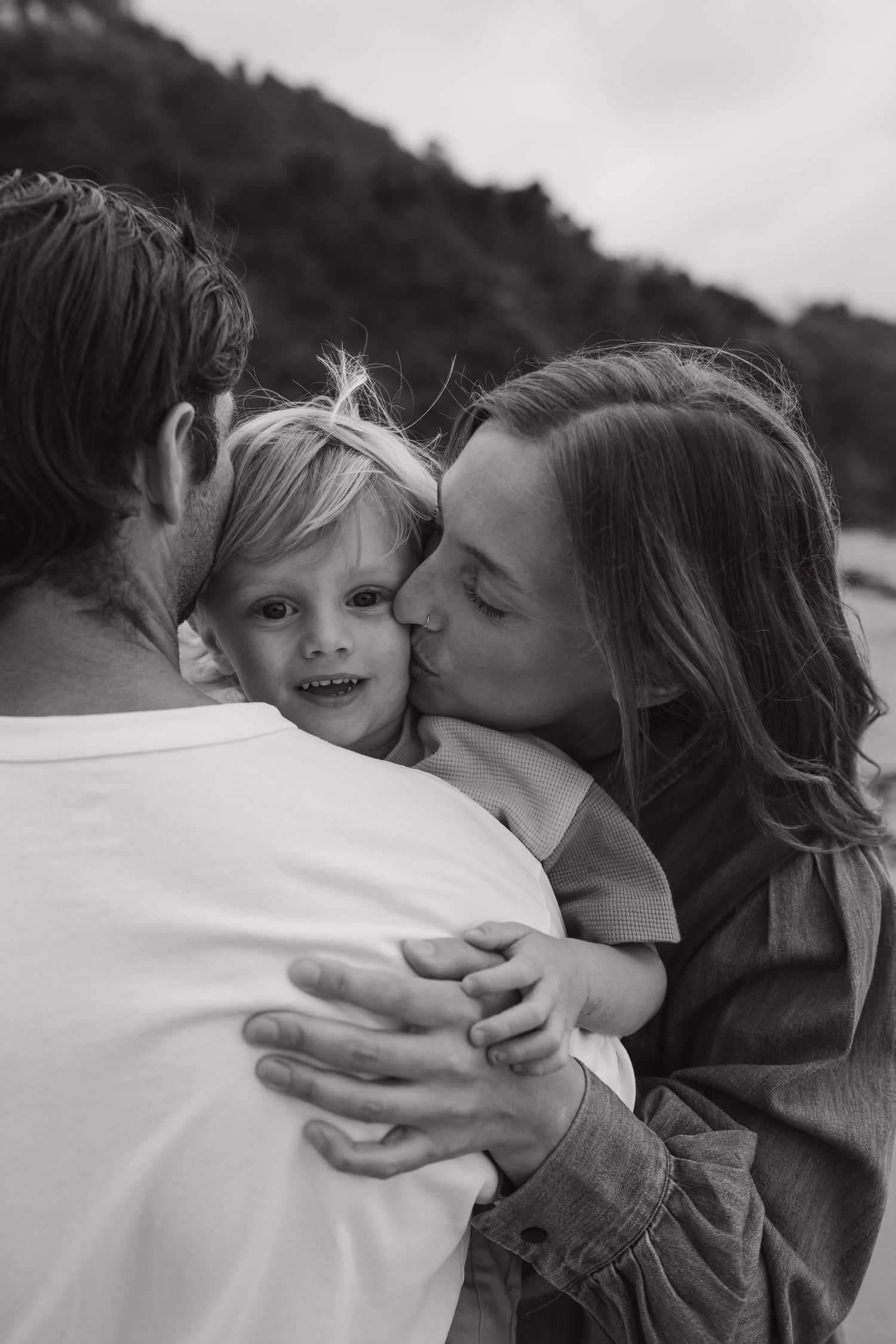 Family sharing loving embraces on the beach in black and white.