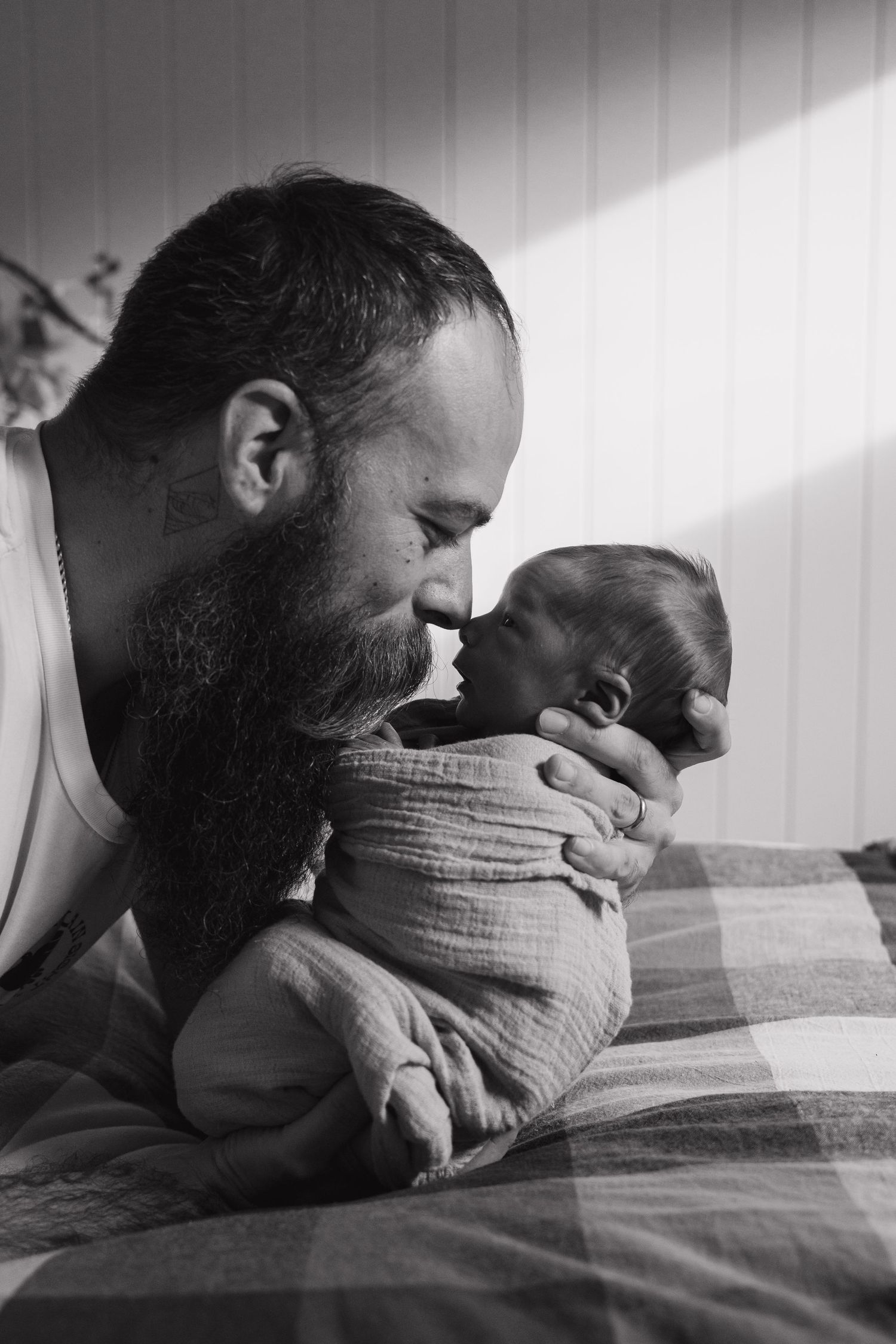 Intimate black and white portrait showing affectionate moment between father and baby.