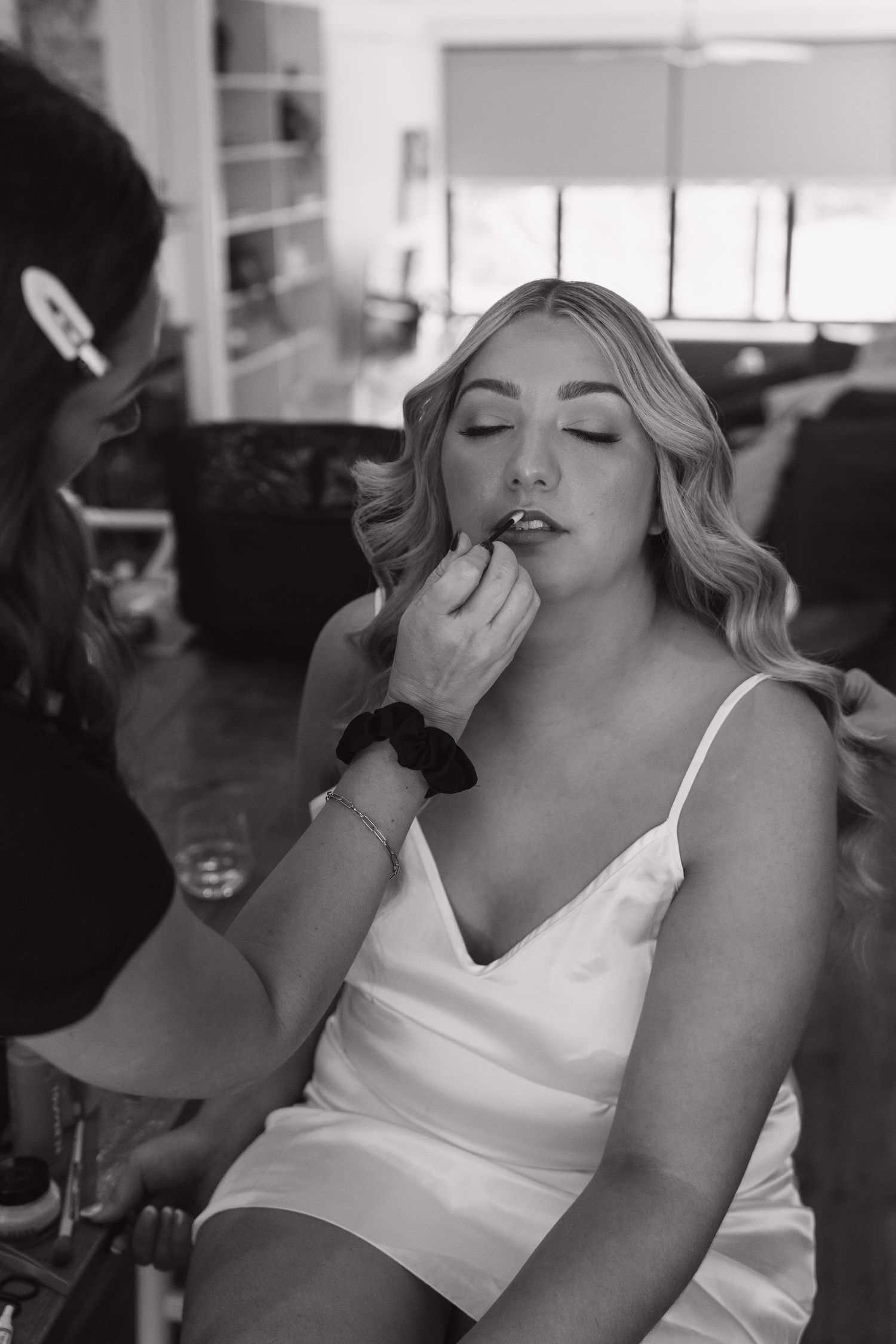 Wedding day makeup preparation scene in black and white.