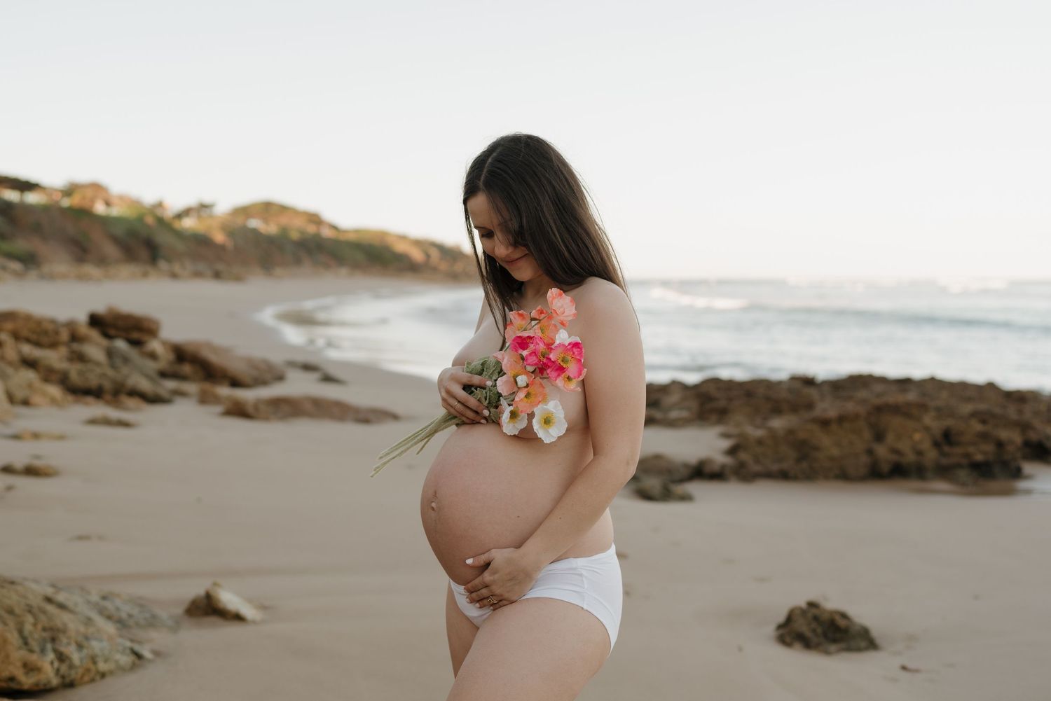 Maternity photoshoot on a rocky beach with flowers.