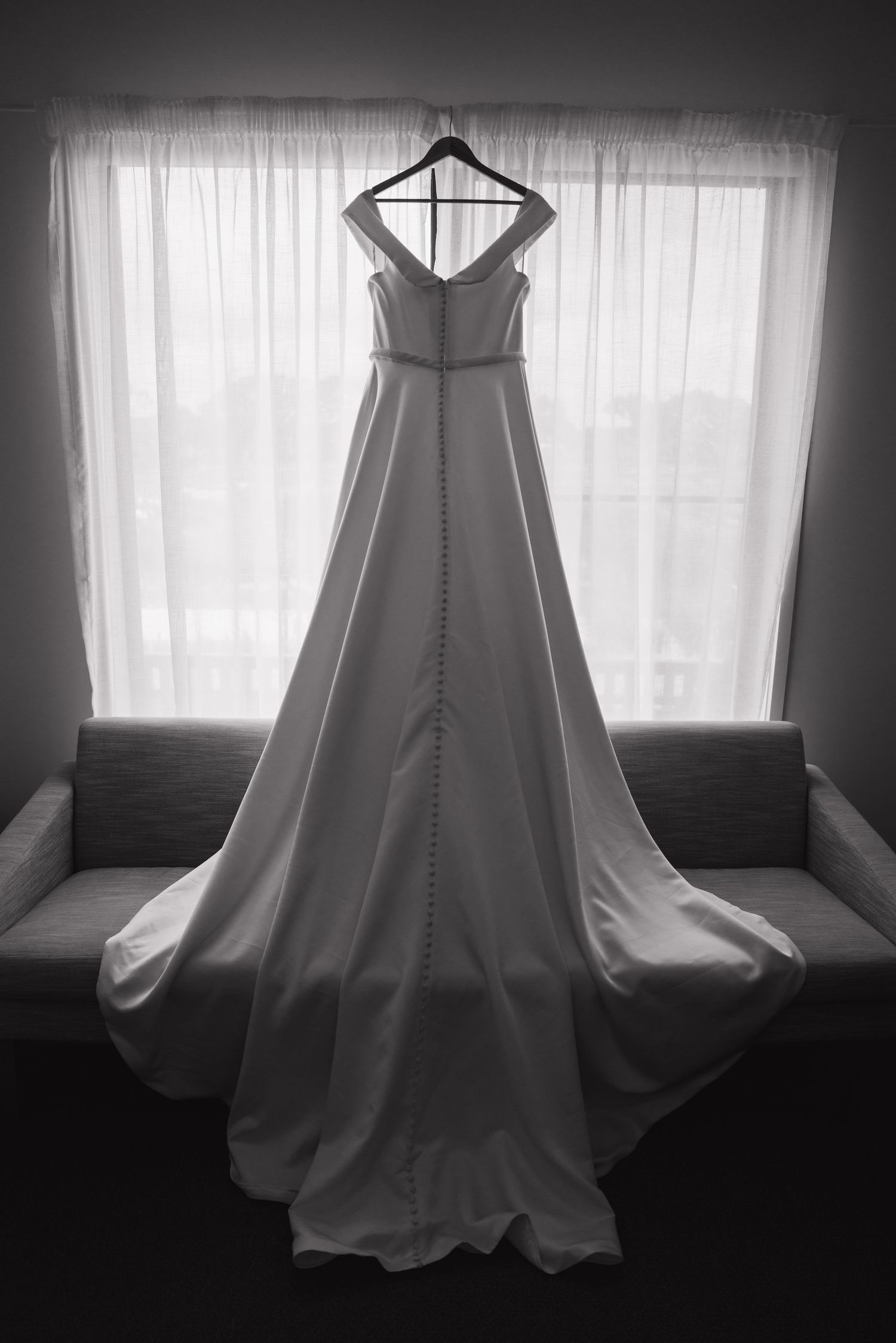 Wedding dress silhouette displayed against window light in dramatic black and white.