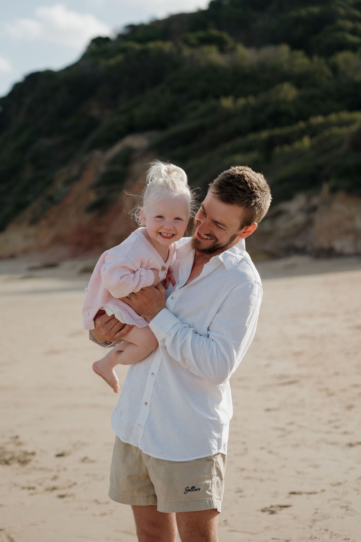 Parent and child sharing a joyful moment on a sunny beach.