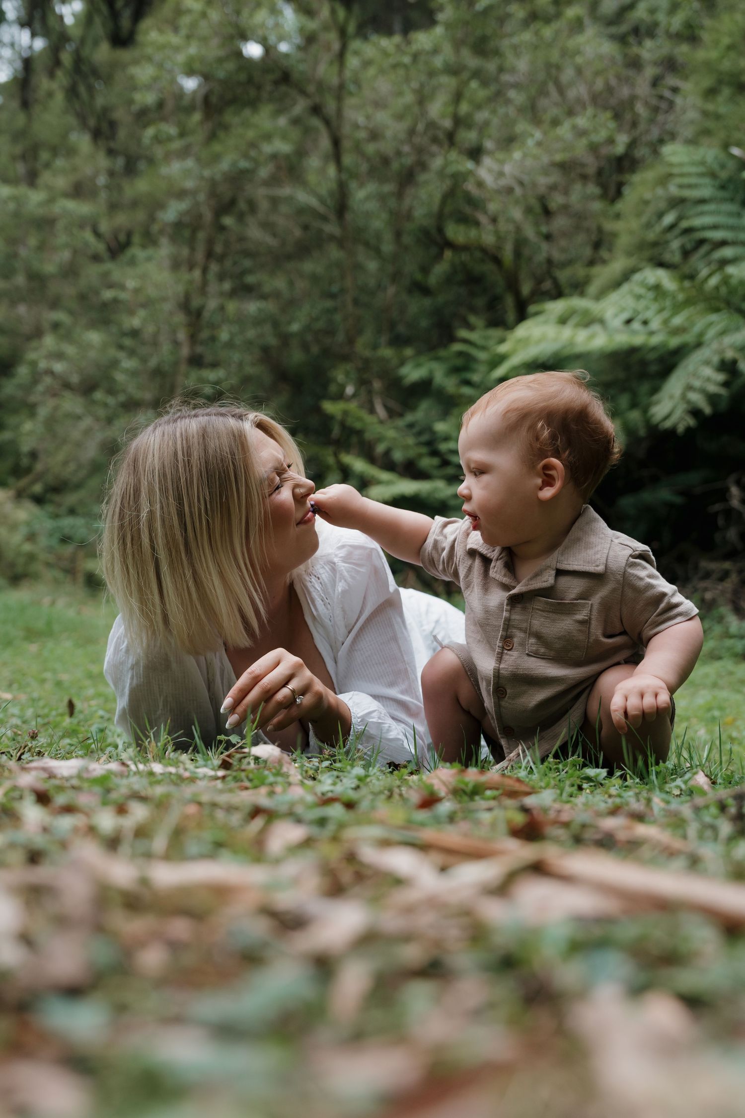 Candid family interaction photographed while resting on forest floor among autumn leaves.