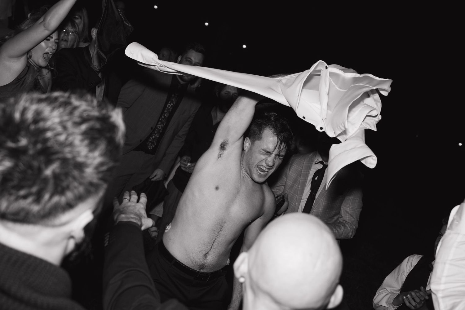 Energetic party scene with people dancing in black and white photography.