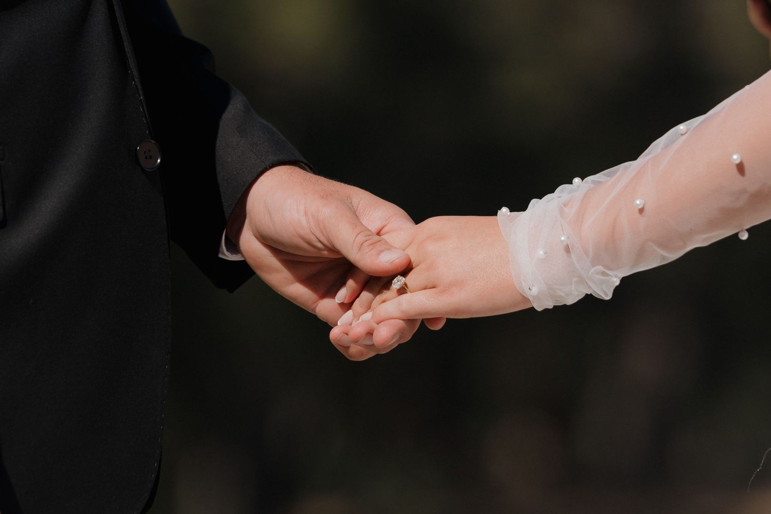 Close-up of hands exchanging rings during wedding ceremony.