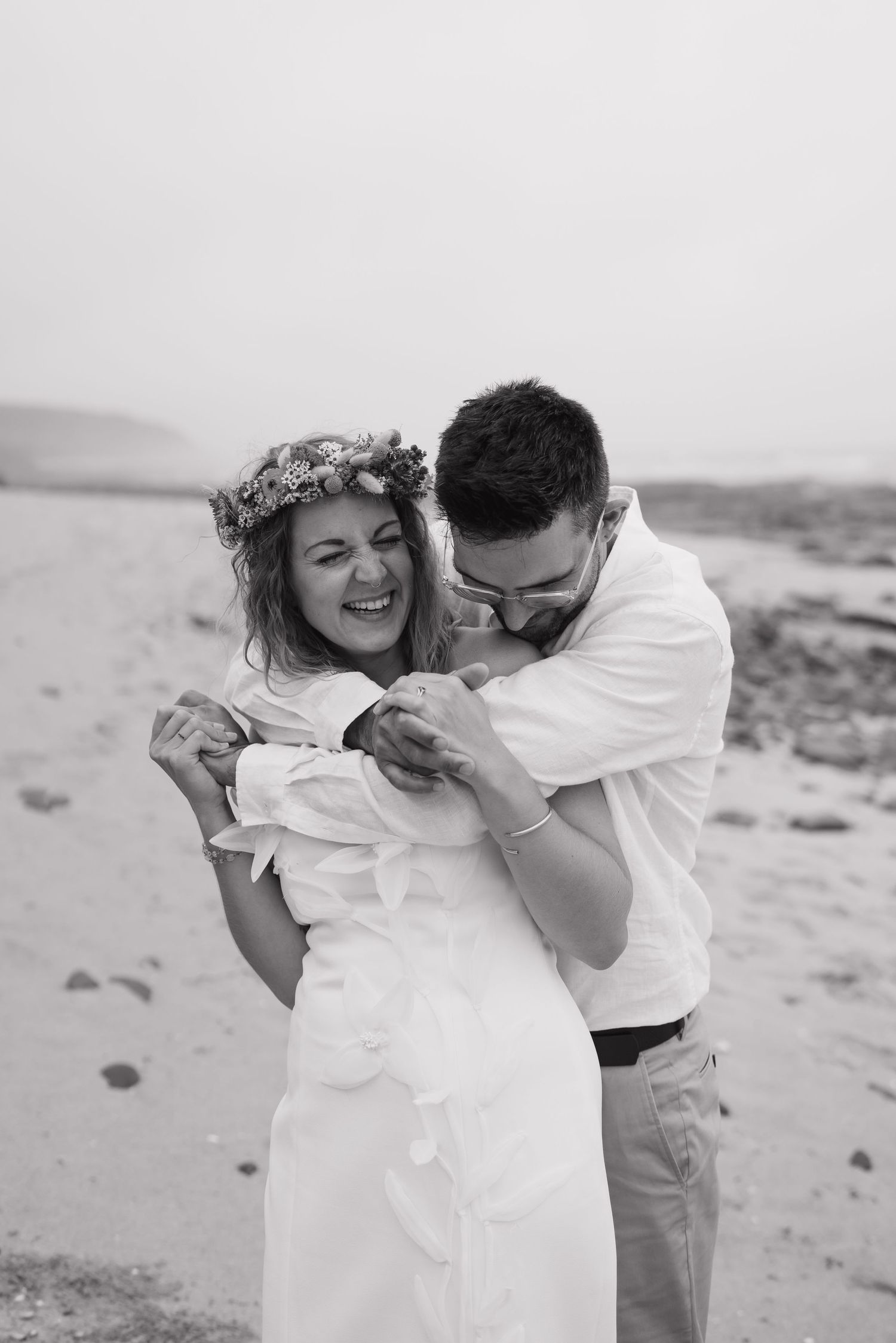 A romantic black and white photo sequence of a couple embracing and laughing together on a beach.