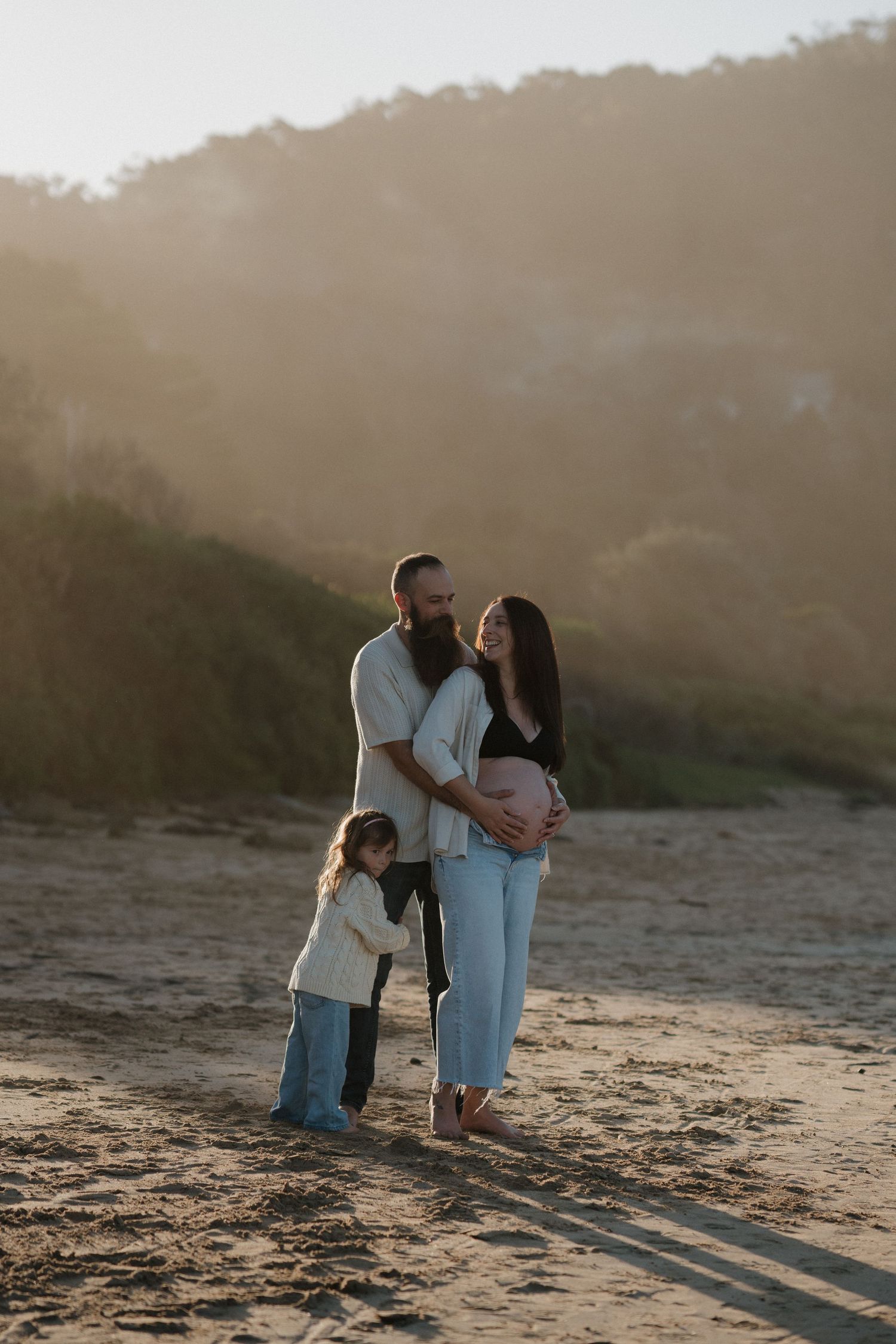 Family silhouetted against golden sunset on beach.