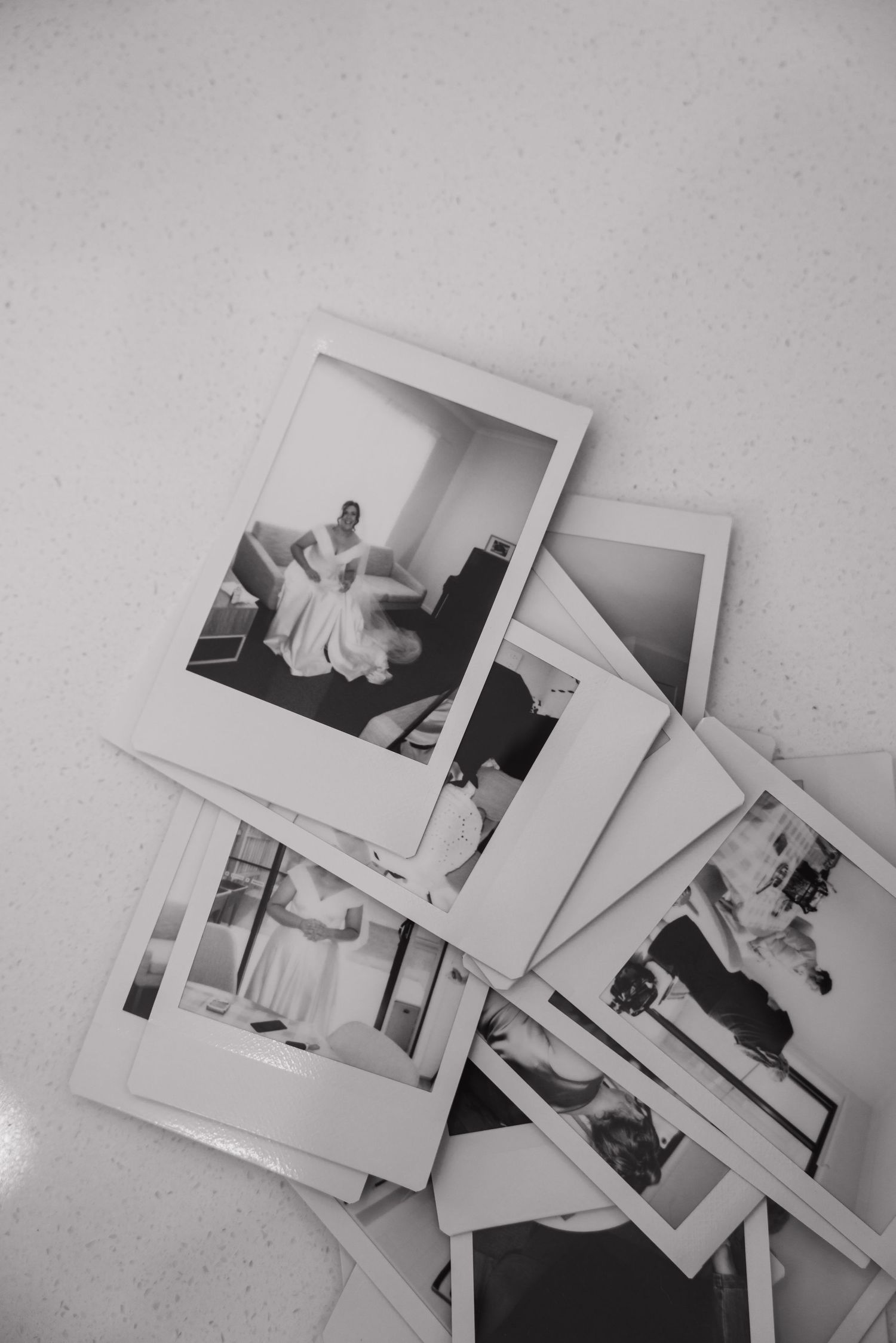 Collection of black and white wedding photographs scattered on light surface.
