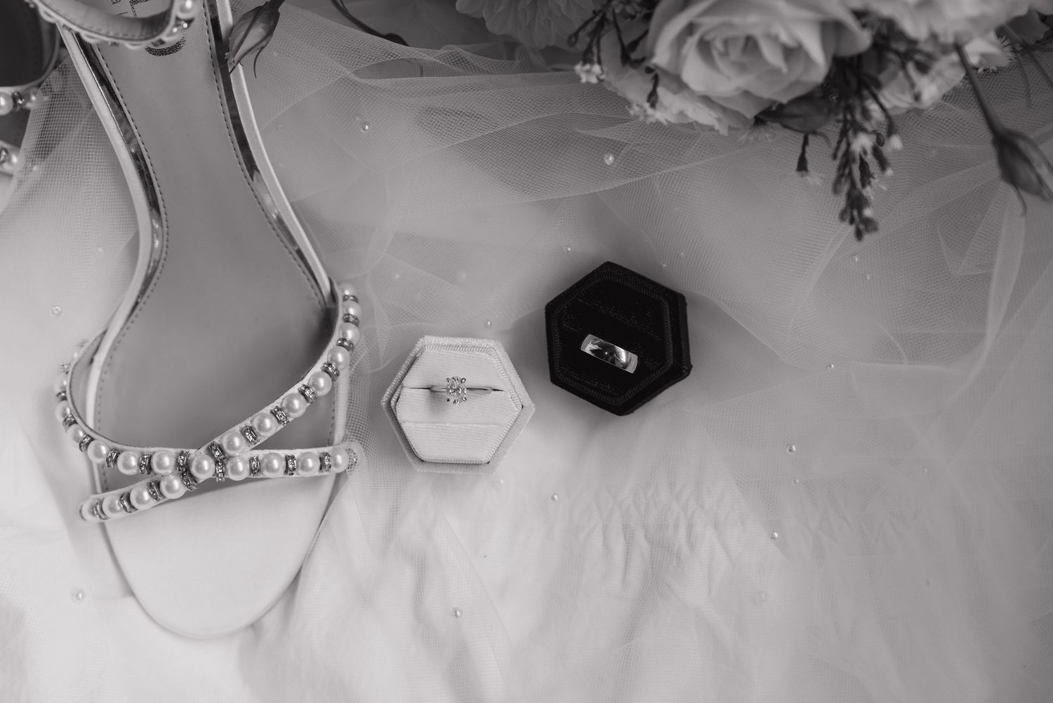 Elegant wedding accessories and jewelry arranged on white fabric.