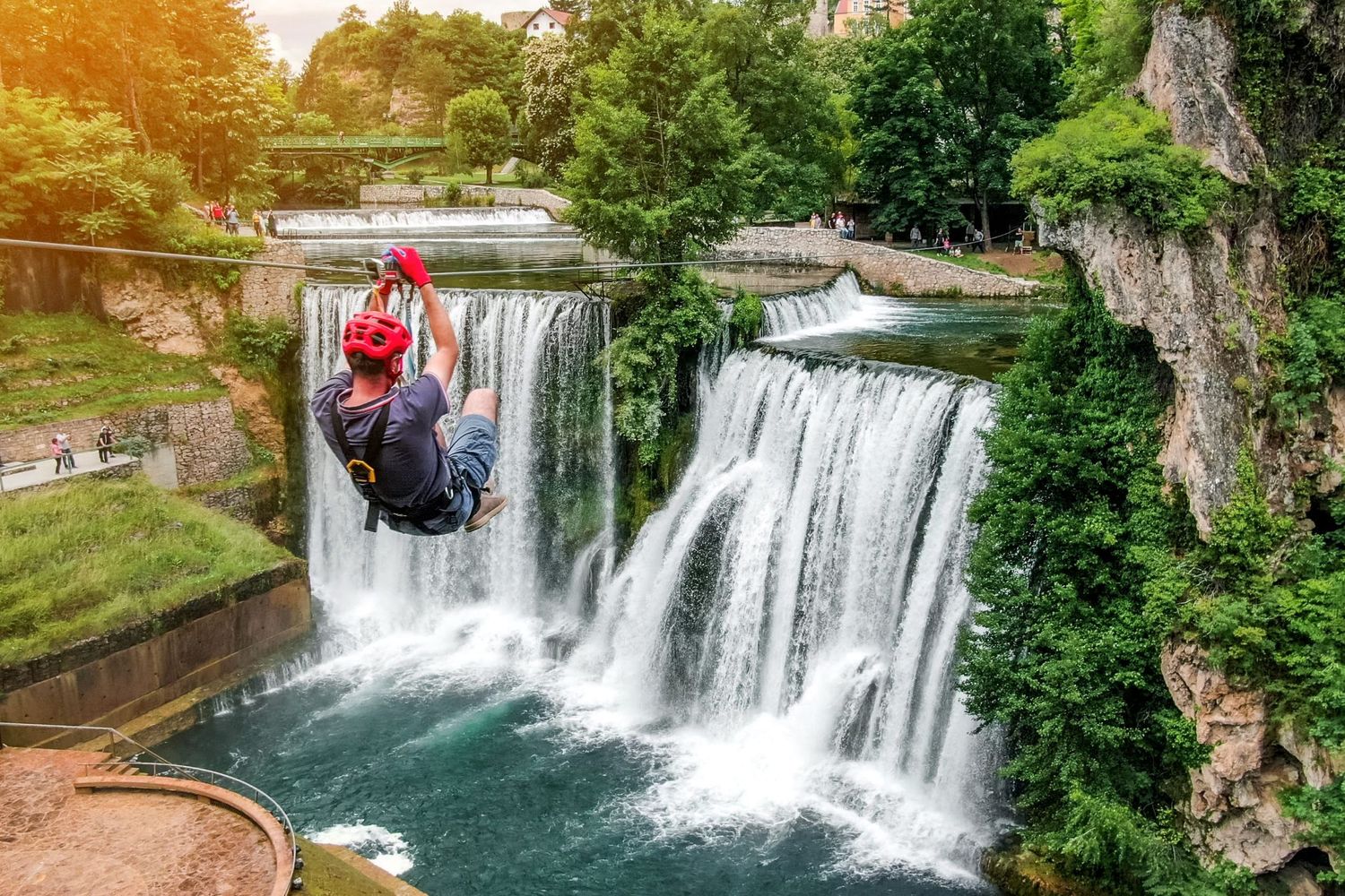 Dramatic waterfall flowing over multiple tiers surrounded by lush greenery and viewing platforms.