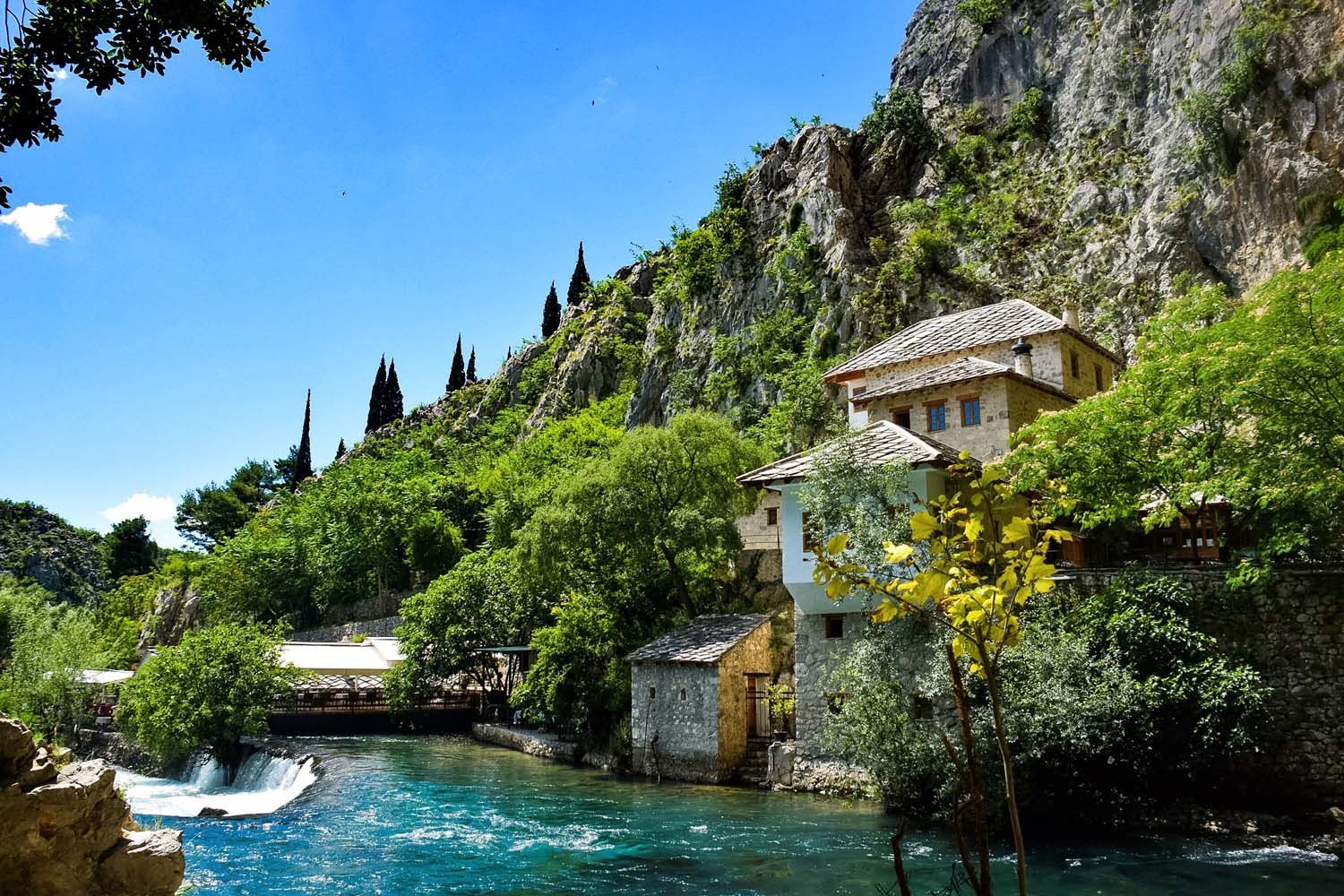 Mediterranean villa perched on rocky cliff above crystal clear turquoise waters.