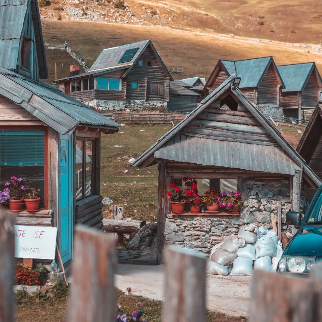 Rustic wooden cabins with metal roofs nestled in a mountainous landscape during autumn.