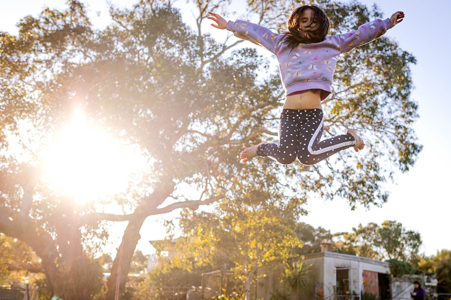Image of a person jumping through the air at sunset with trees in the background.
