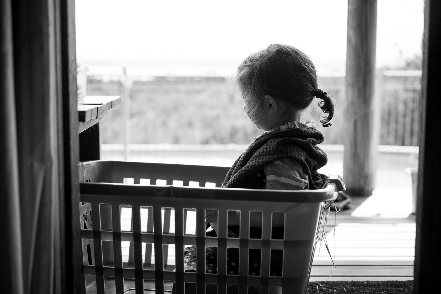 Silhouette by window creates atmospheric indoor portrait.