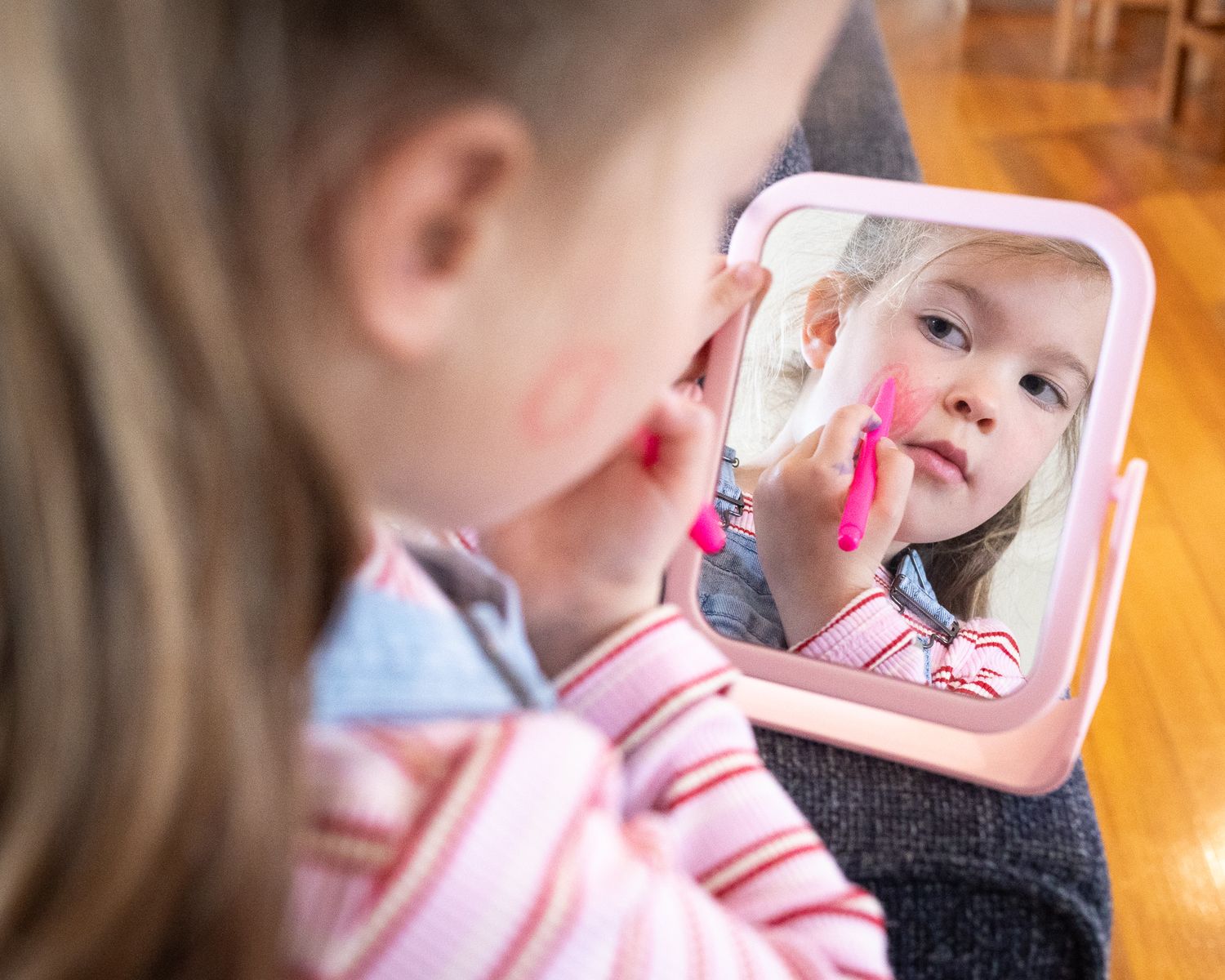 Interior scene of young girl looking into a mirror with soft natural lighting through windows.