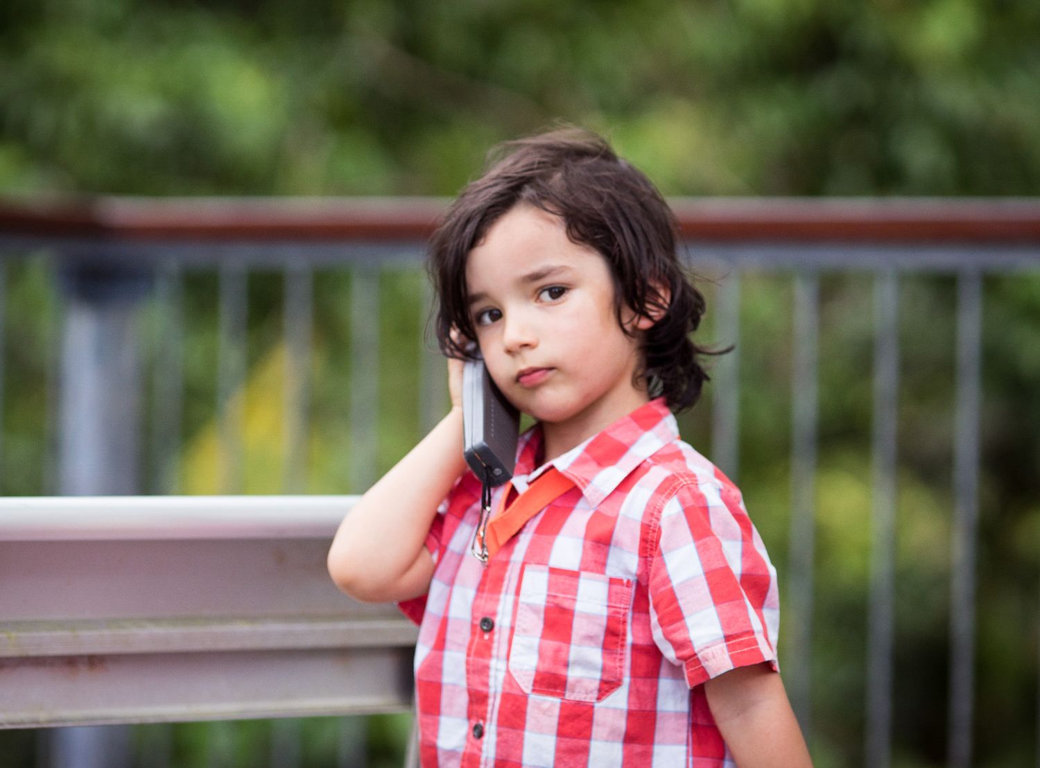 Young boy on the phone outdoors.