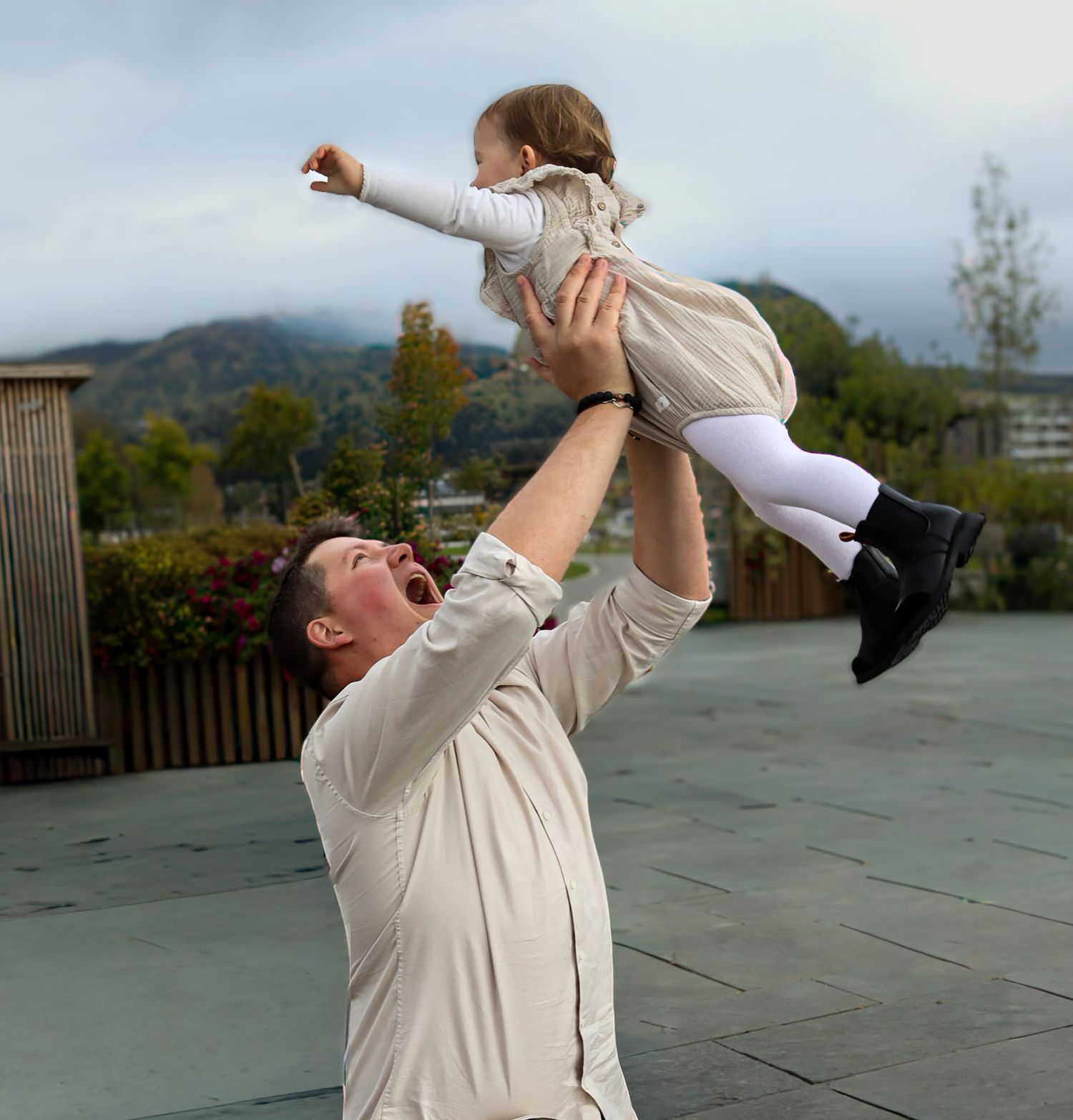 Far som løfter babyen sin opp i luften under familiefotografering i Mjøsparken.