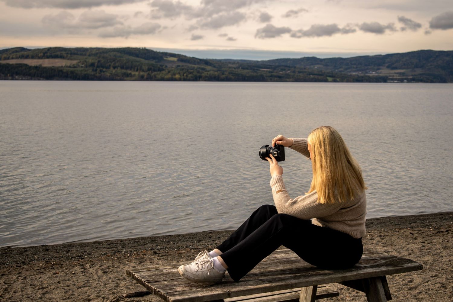 Fotograf Amalie fra Photo by Rime sittende ved vannet med kamera.