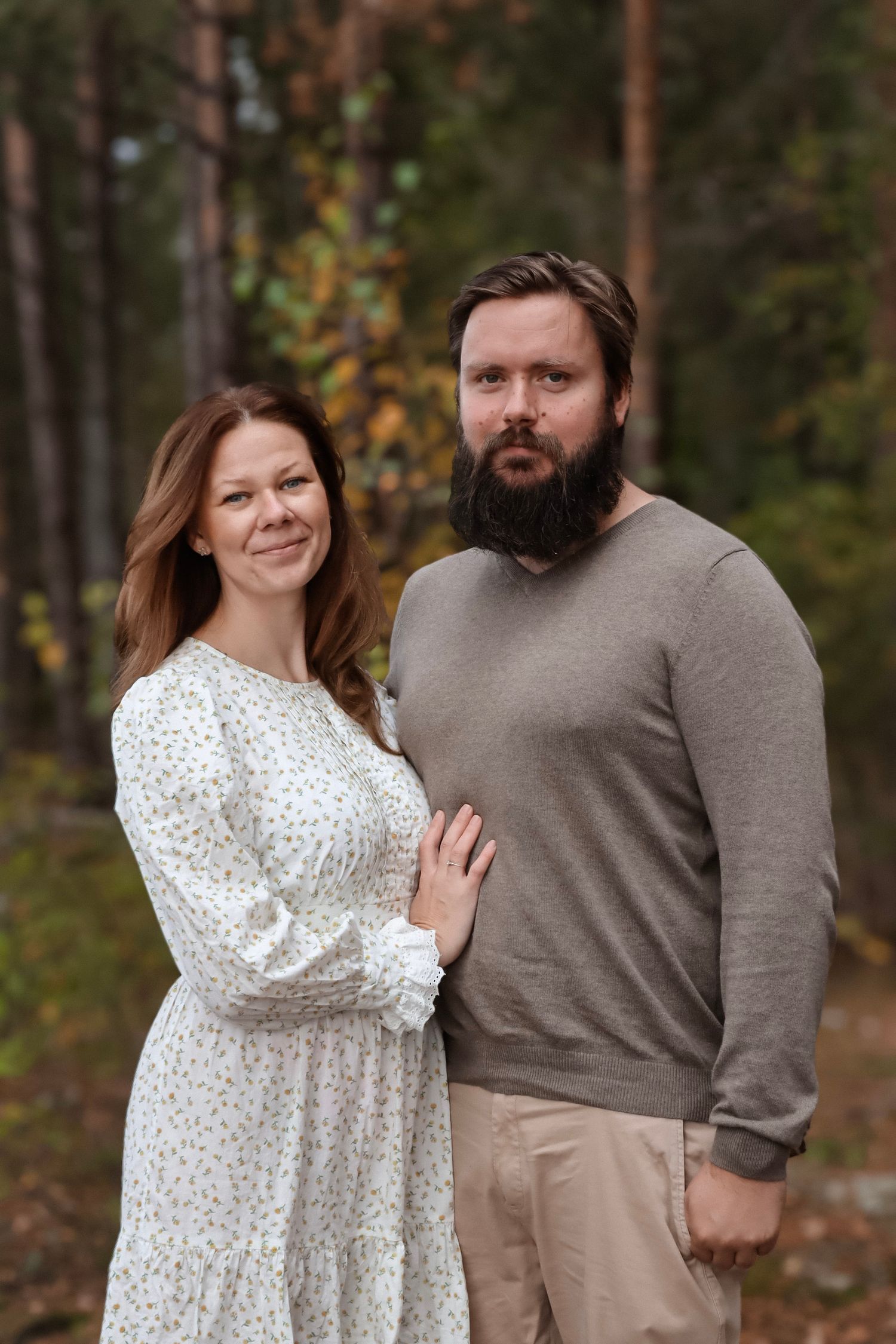 Par fotografert sammen i en høstskog, med kvinnen i blomstrete kjole.