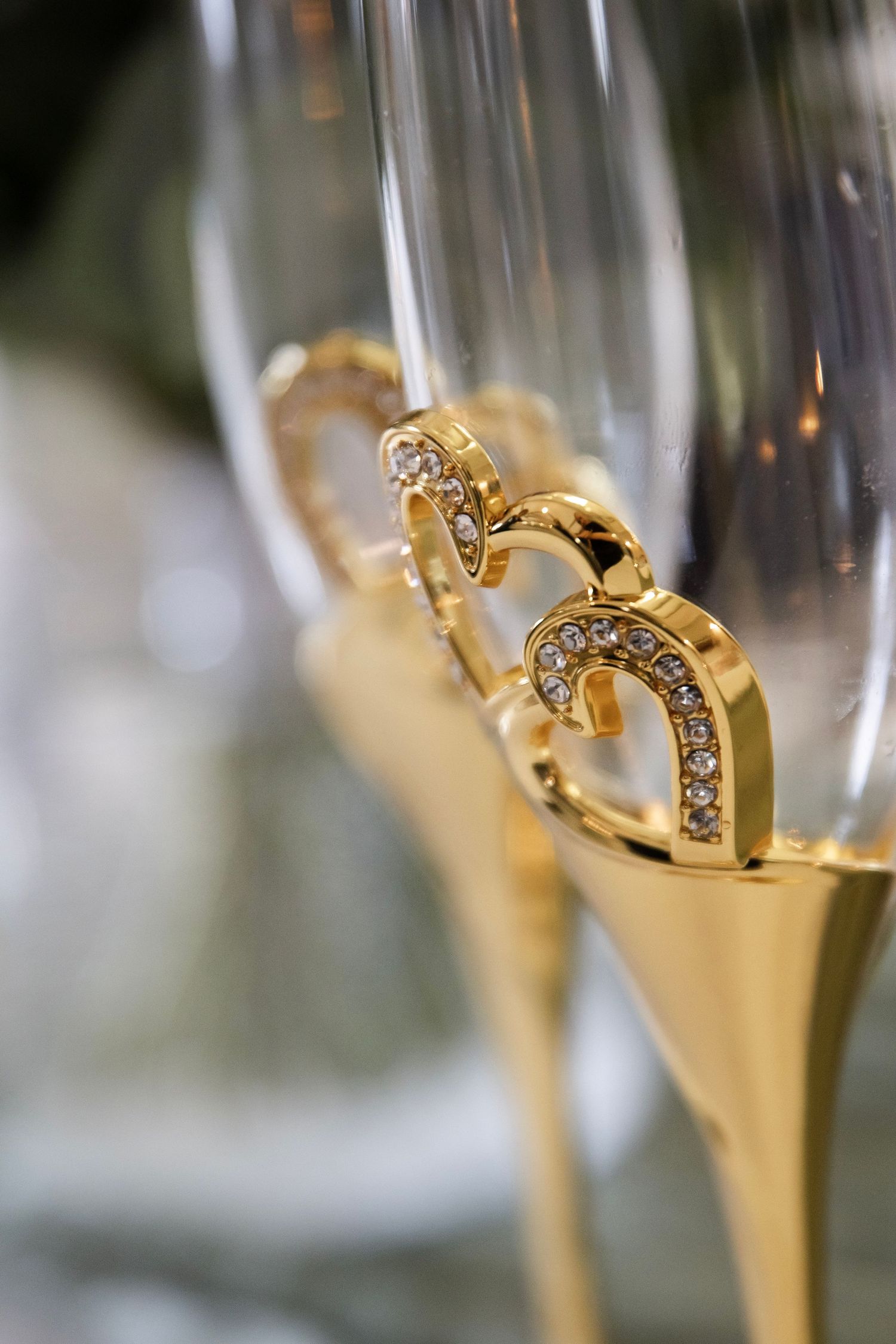 Champagneglass i gull med hjerteformede detaljer fotografert under bryllupsfeiring.