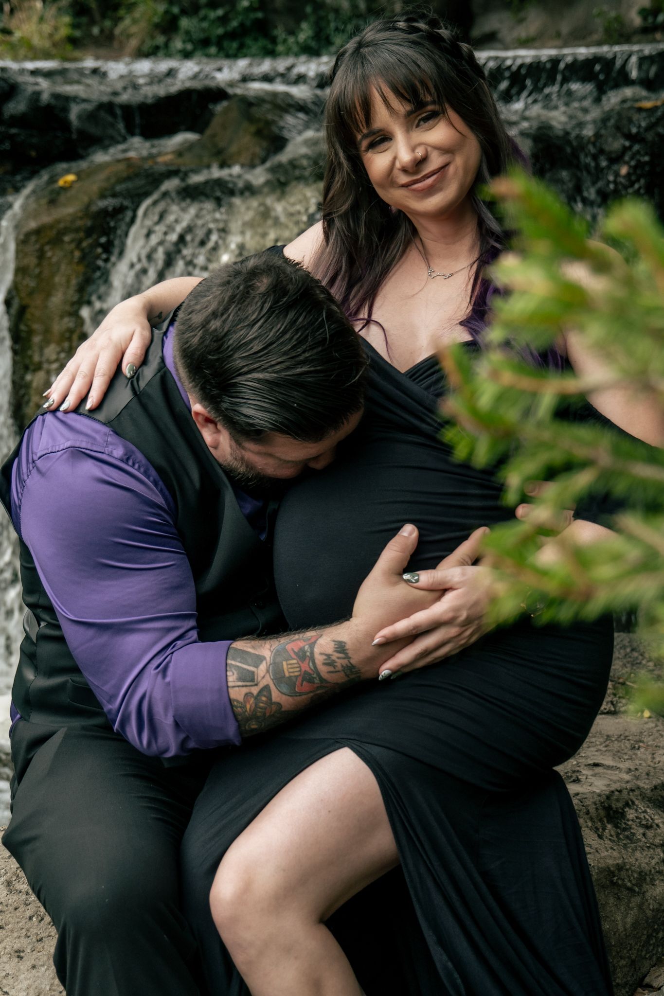 Intimate maternity photo session by a waterfall with natural scenery.