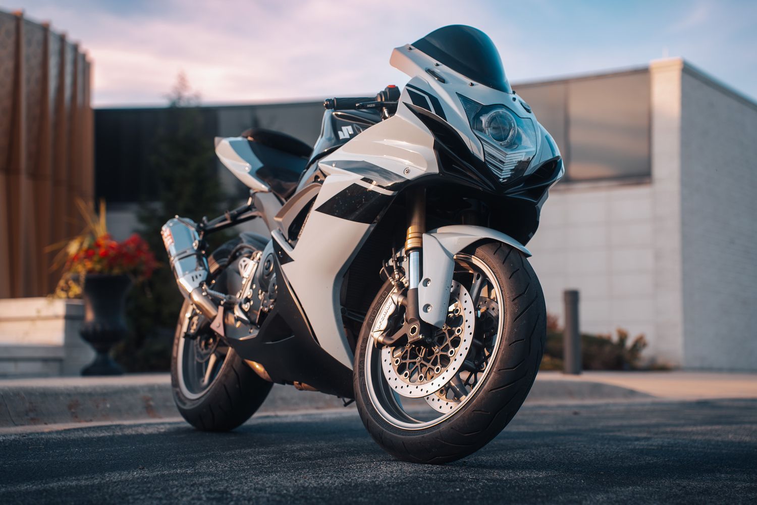 Sport motorcycle parked in front of modern building during dusk.