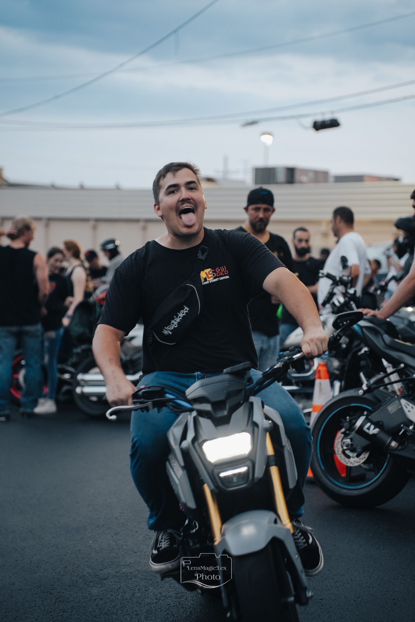 Motorcyclists gather at a bike meetup in a parking lot at dusk with sport bikes and custom motorcycles on display.