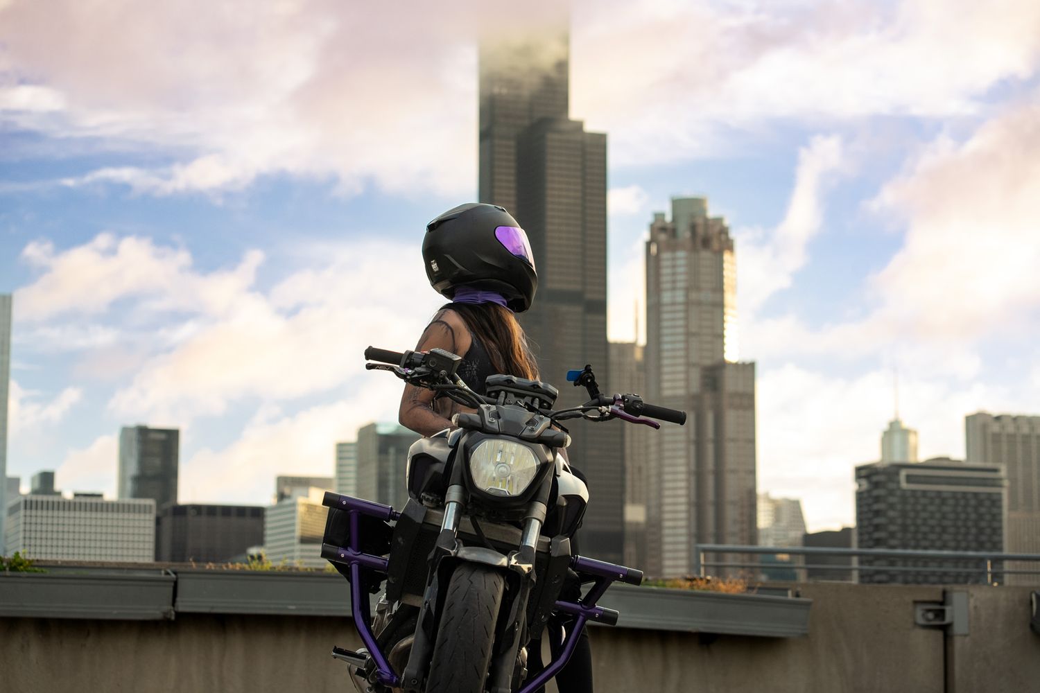 A motorcycle rider on their bike silhouetted against Chicago's iconic Willis Tower.