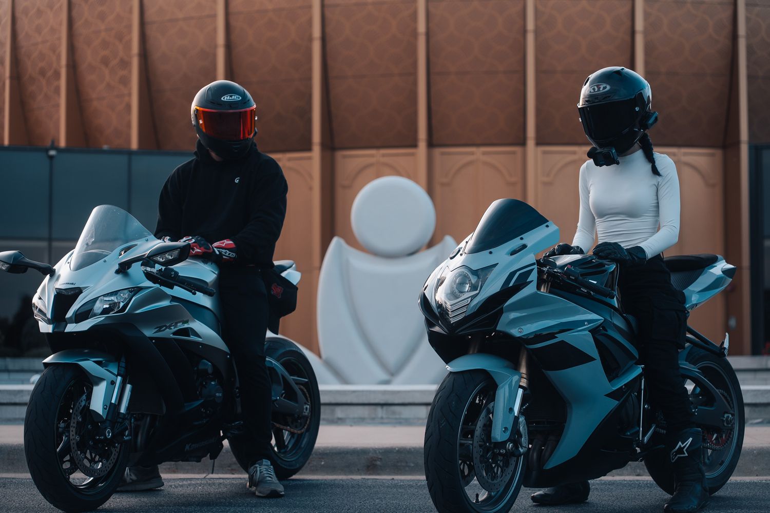 Multiple motorcycles lined up against an urban building backdrop.