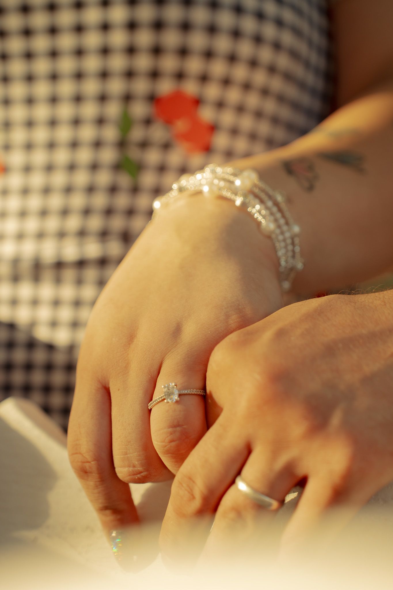 Close-up sequence of hands wearing delicate rings against a checkered background.