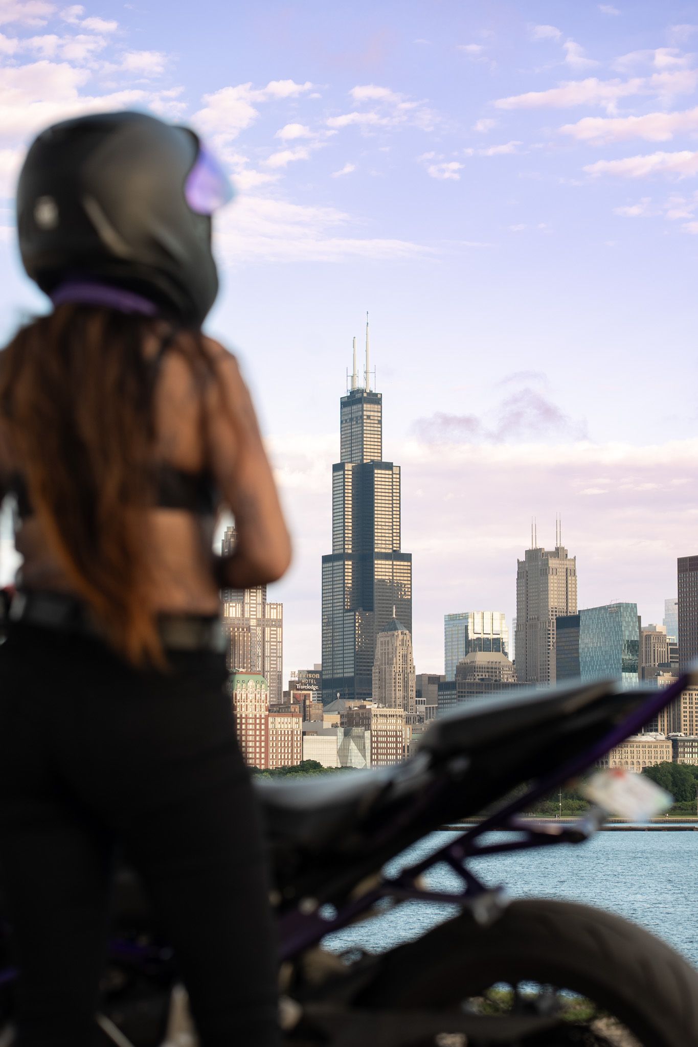 Urban motorcycle scene with Chicago's iconic Willis Tower and lakefront in background.