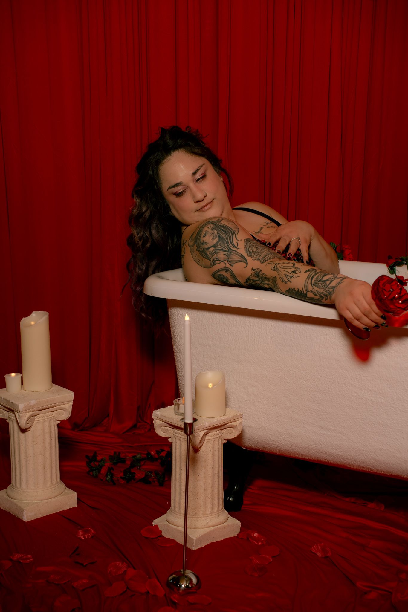 A series of artistic boudoir photos with red curtain backdrop shows a person reclining in a white bathtub.