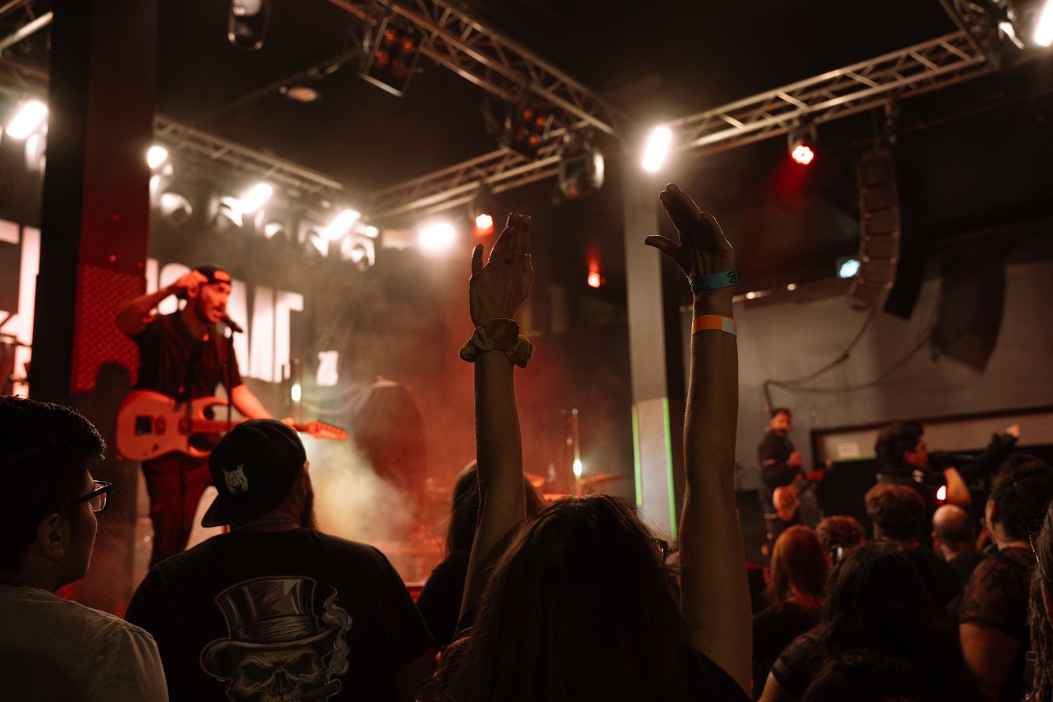 Concert crowd silhouetted against bright stage lights in a dark venue.