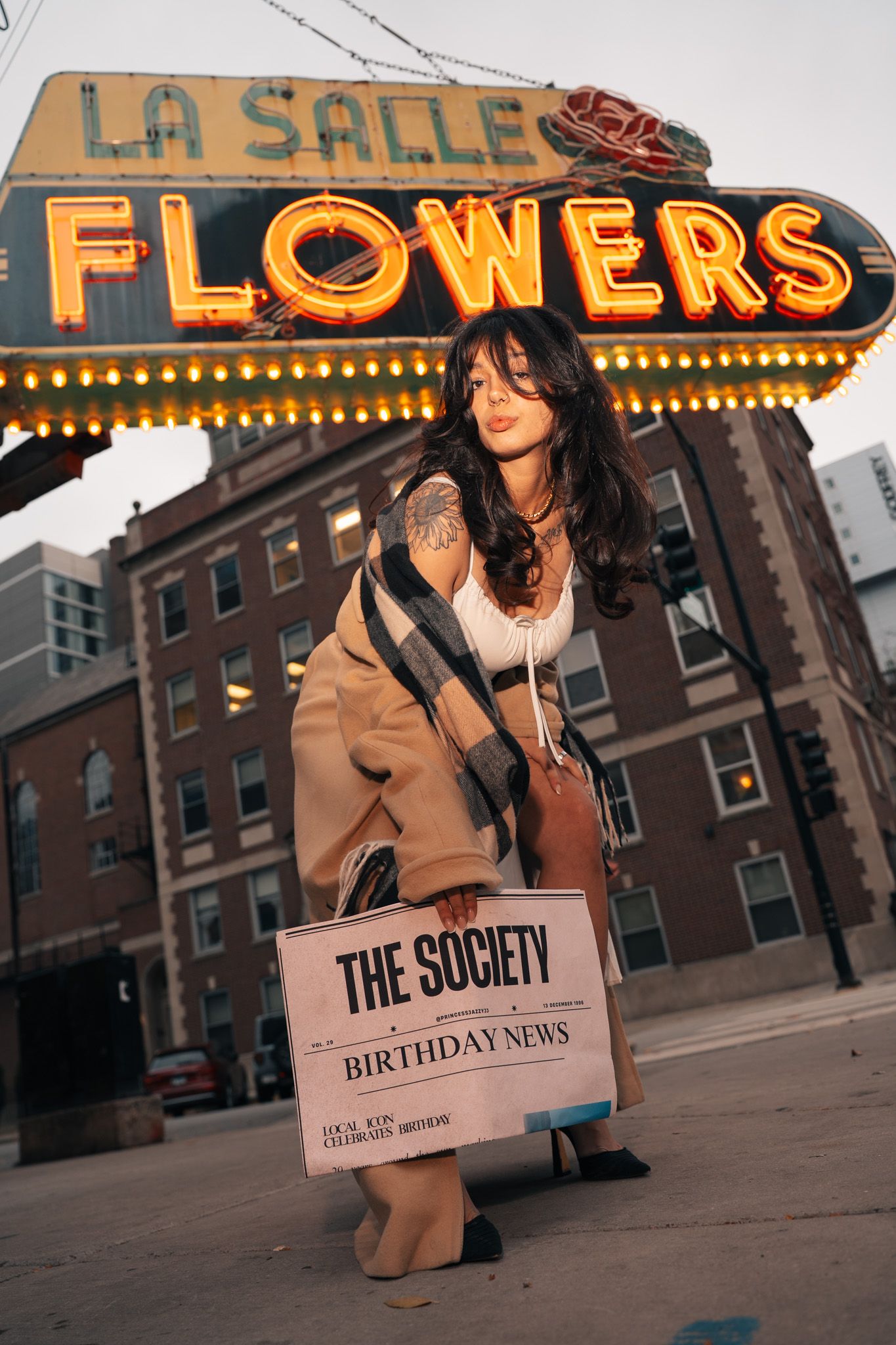 Urban street scene with neon signs for 'La Salle' and 'Flowers' glowing against brick buildings at dusk.