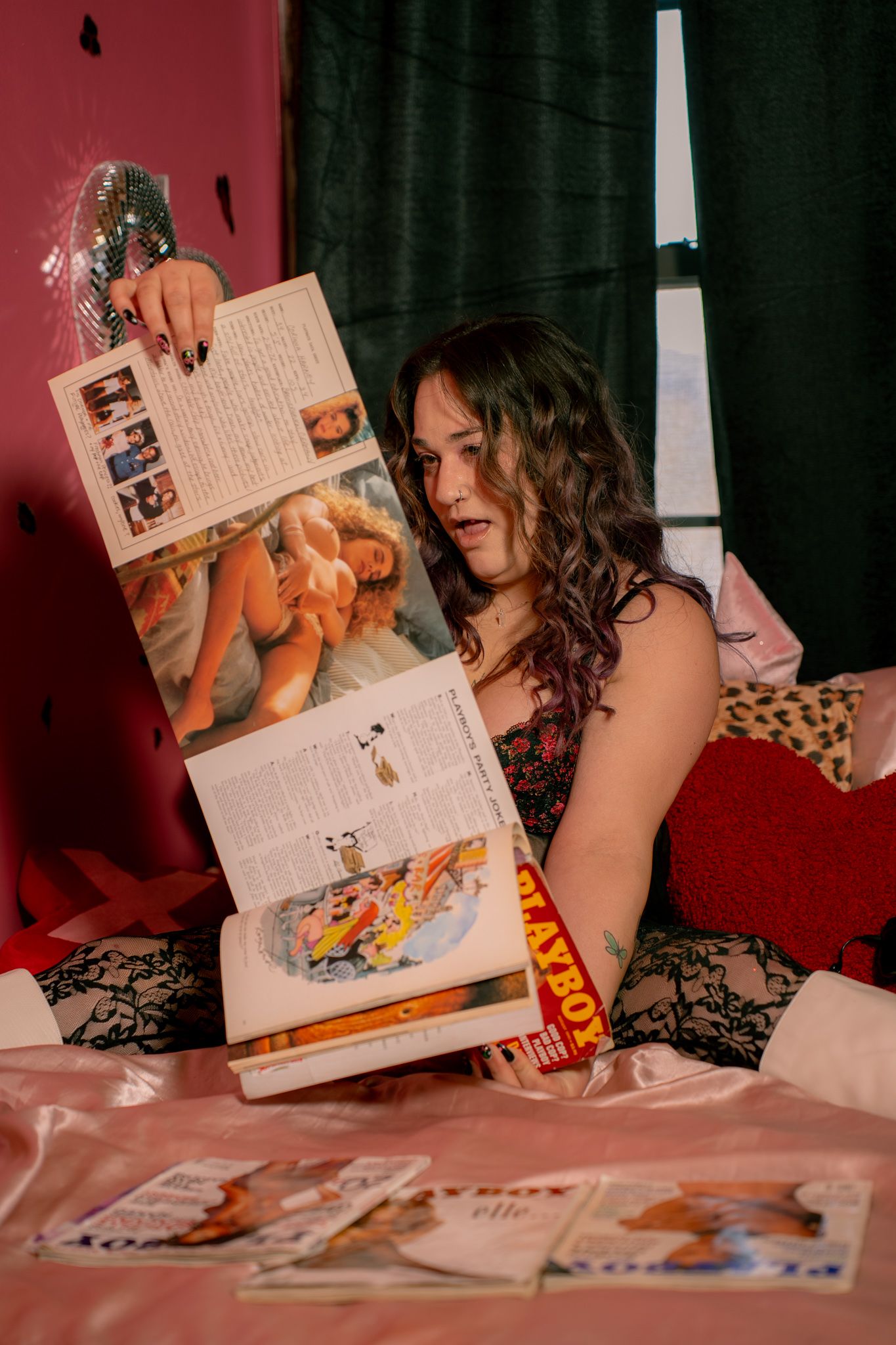 A person in a dark room reads a magazine while lying down on a red-tinted surface.