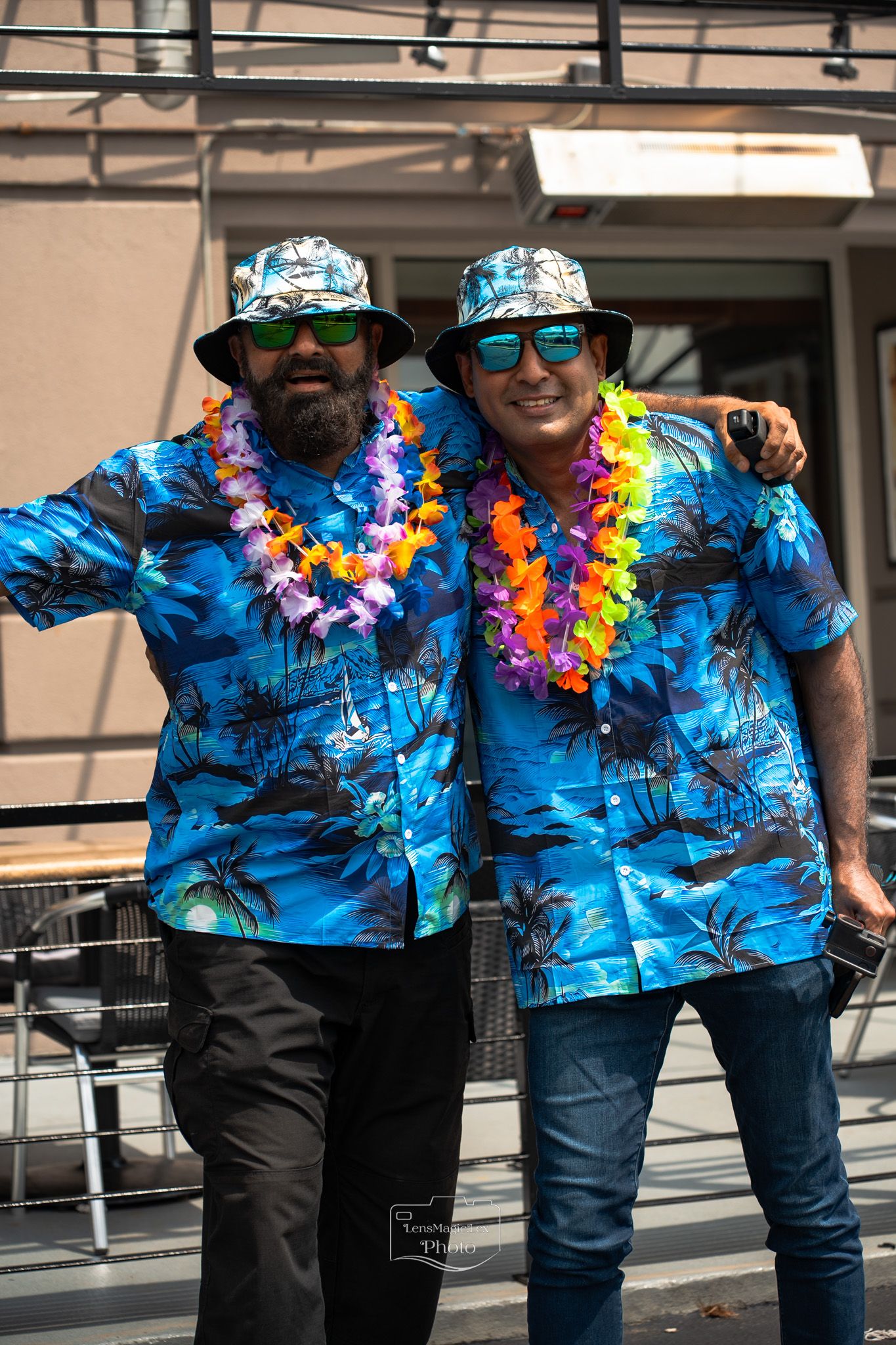 People wearing matching blue Hawaiian shirts and lei necklaces at a tropical themed party.