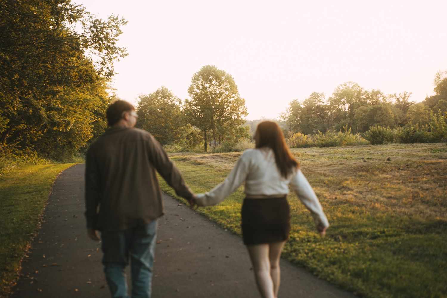Two people walk together on a path during golden hour in a natural setting.