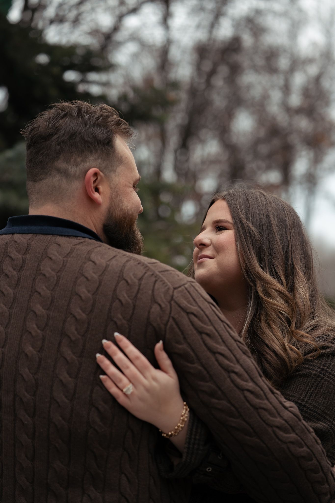 A couple in brown sweaters share intimate moments during a romantic outdoor photoshoot in winter.
