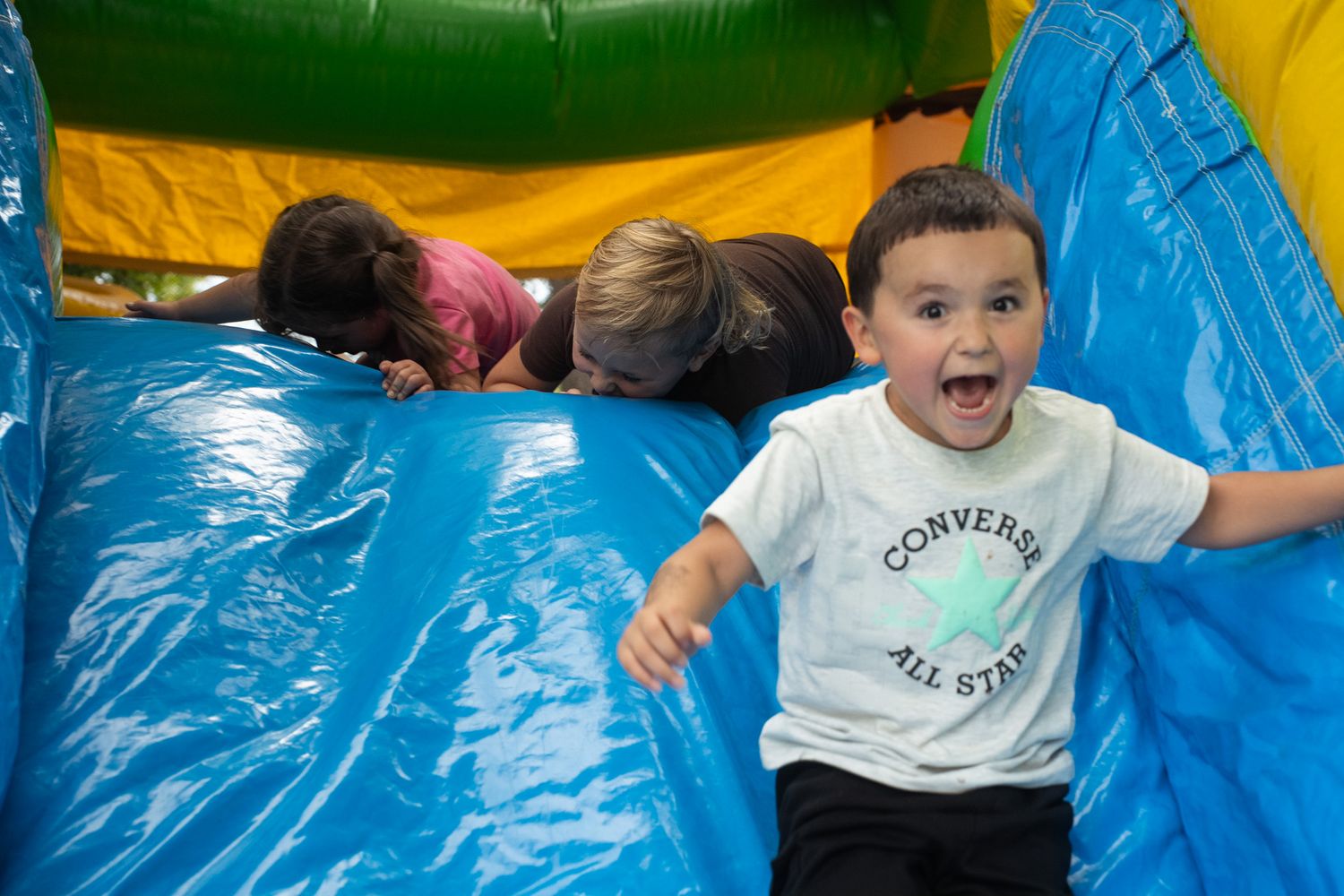 Kids enjoying themselves on a colorful inflatable bounce house outdoors.